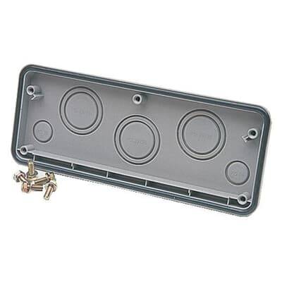 Graue rechteckige Abdeckung mit mehreren runden Erhebungen, neben einigen Schrauben auf einer Oberfläche liegend.