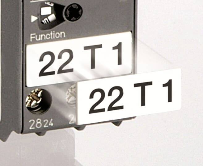 Ein elektrisches Bauteil mit der Aufschrift '22 T1', darunter zwei verdrahtete Anschlüsse. Im oberen Bereich ist ein Schalter.