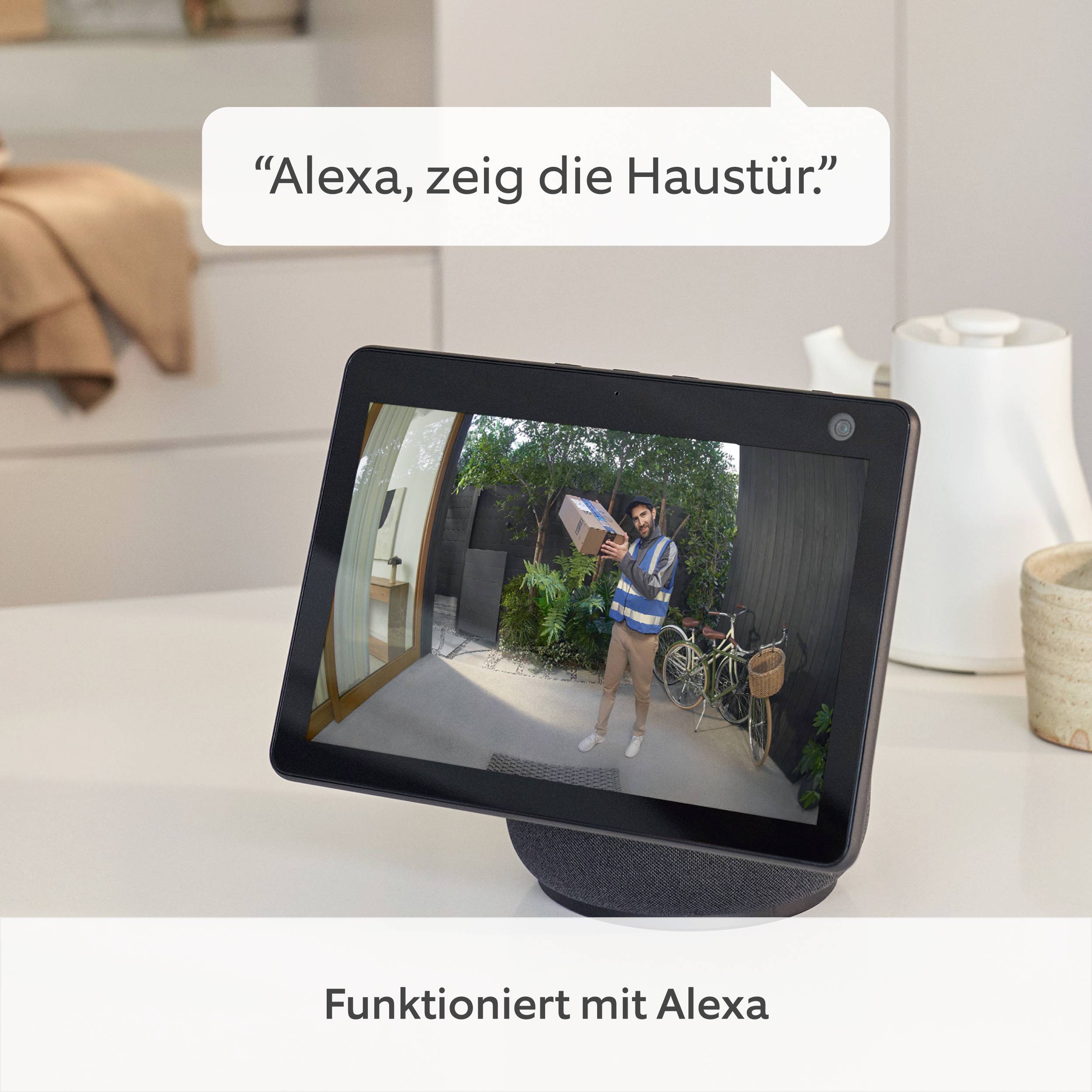 Ein Bildschirm zeigt einen Paketboten vor einer Tür. Oben steht 'Alexa, zeig die Haustür.' Unten: 'Funktioniert mit Alexa'.