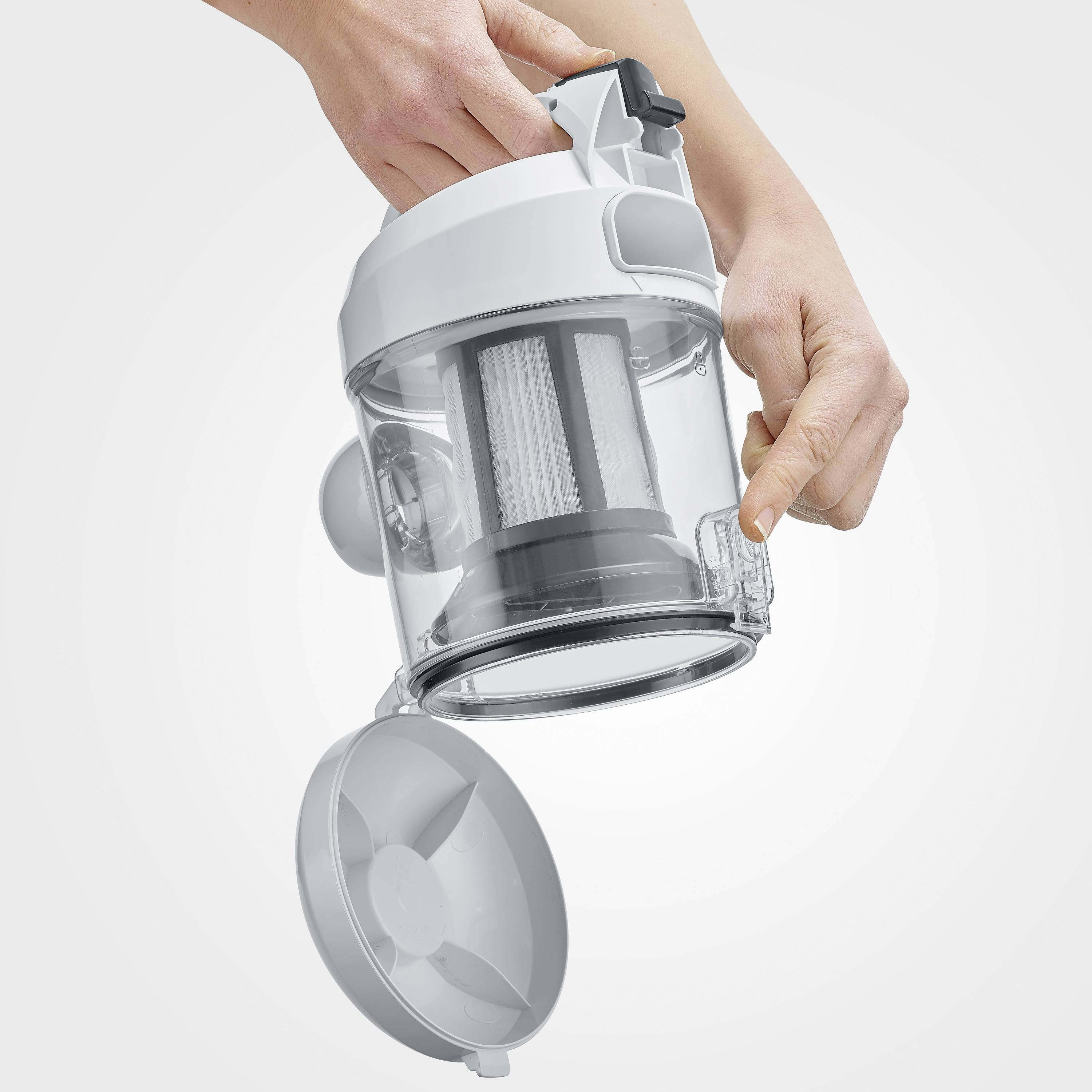 Eine Hand hält einen Staubsaugerbehälter über einem Mülleimer, bereit zur Entleerung, um Staub und Schmutz zu entfernen.