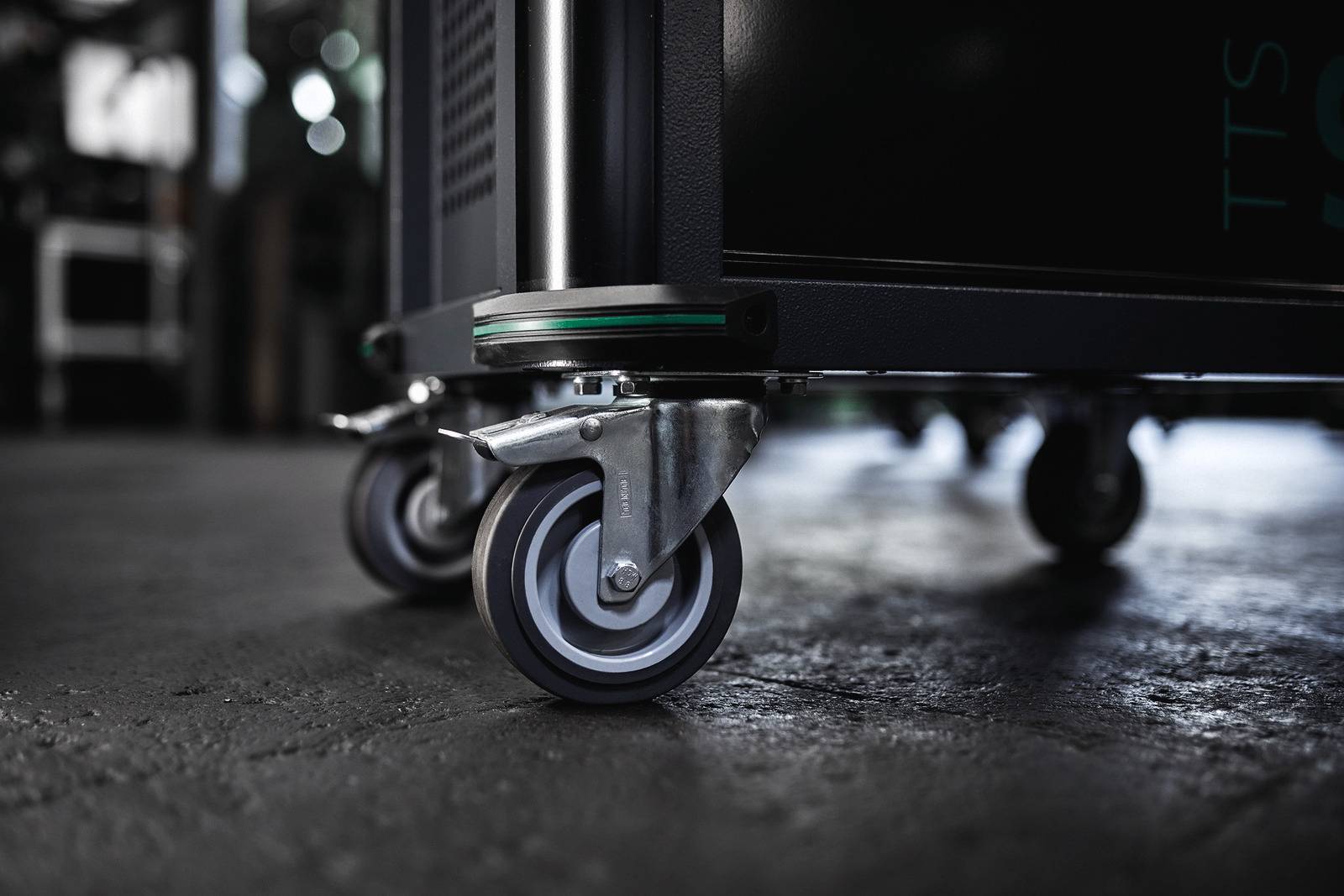 Rollcontainer mit arretierbaren Rädern auf einem Betonboden; Nahaufnahme zeigt robuste Bauweise, geeignet für industrielle Anwendungen.