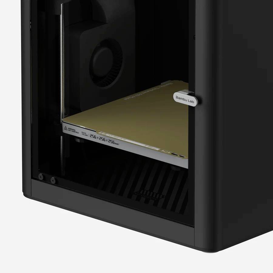 Schwarzer 3D-Drucker mit offenem Gehäuse, der linke Ausschnitt zeigt die Druckplattform und Düse im Inneren.
