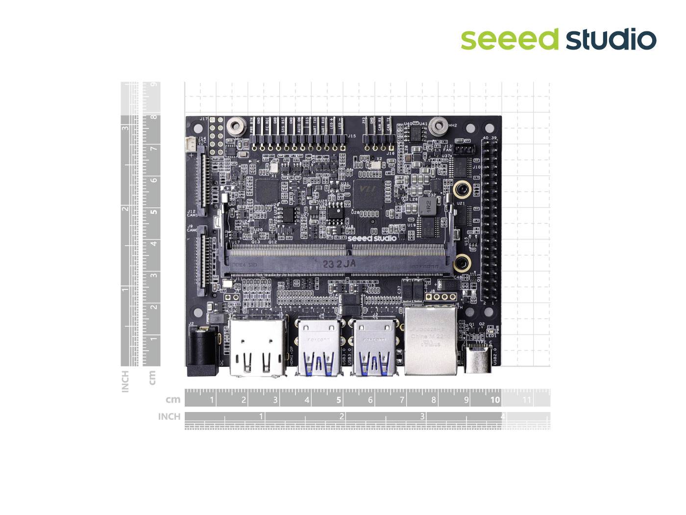 Ein schwarzes Entwicklerboard mit zahlreichen Anschlüssen und Chips ist von Linealen in Zoll- und Zentimetermaßen umgeben.