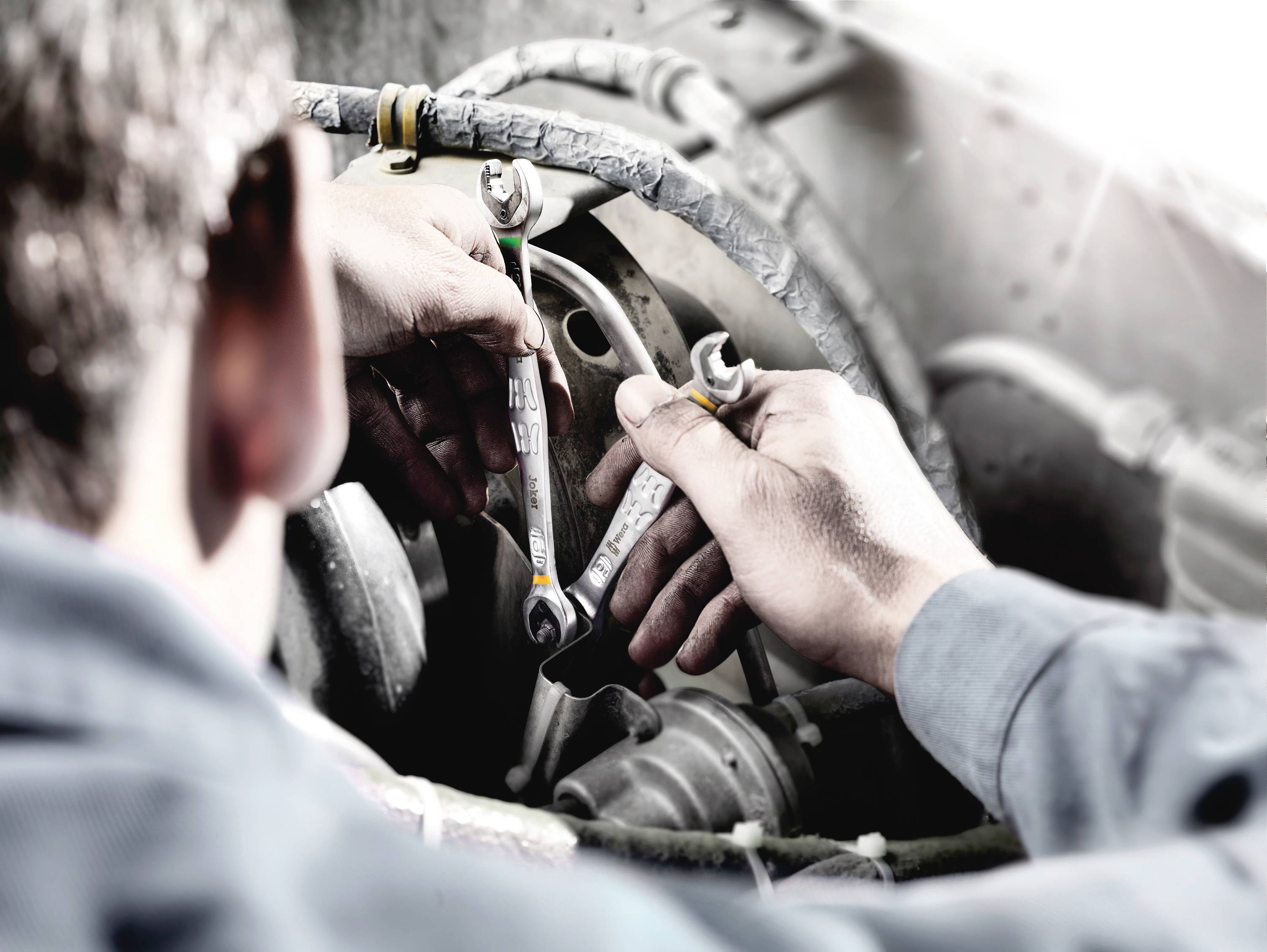Mechaniker arbeitet mit Schraubenschlüsseln an einem Motor.