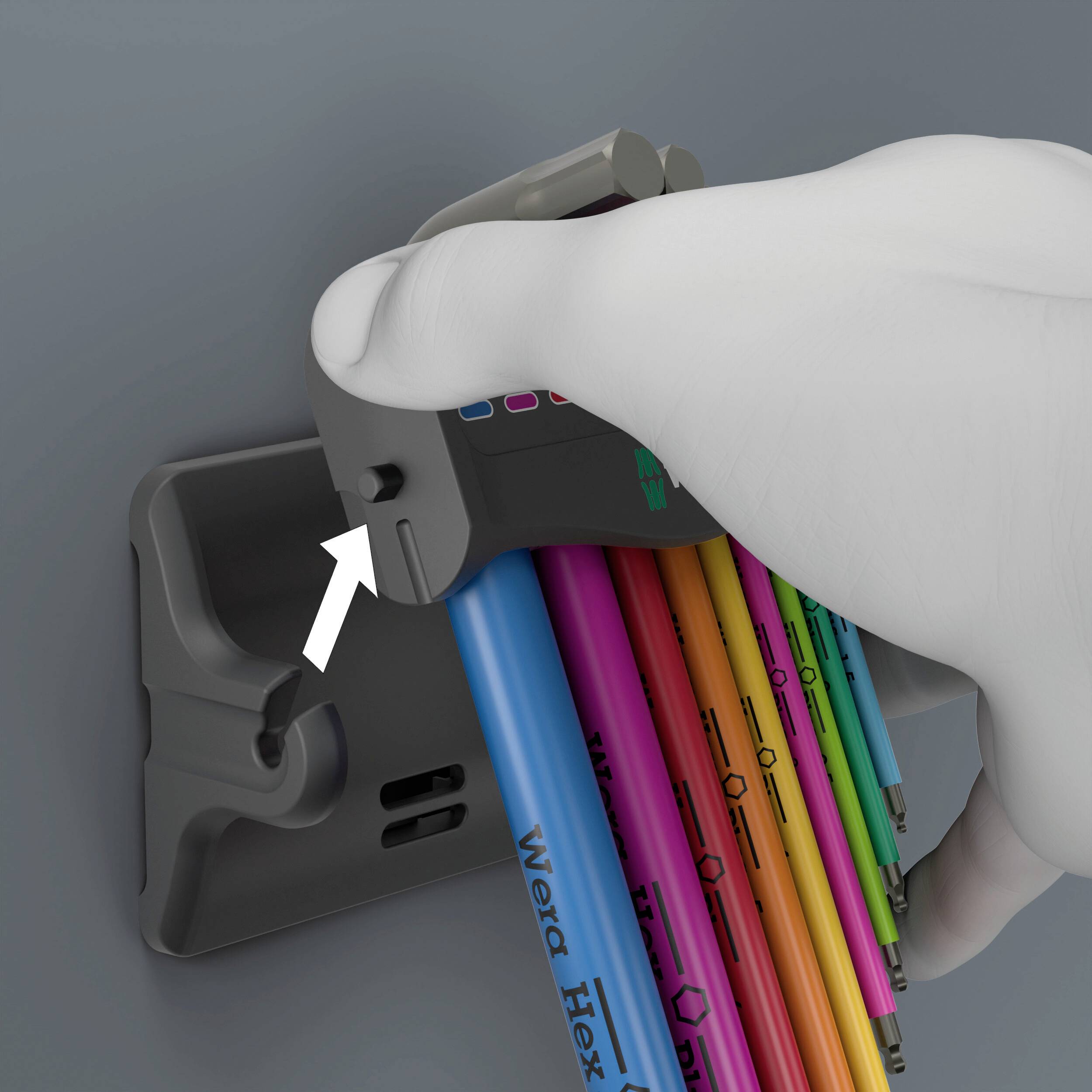 Eine Hand entnimmt einen farbigen Stiftschlüssel aus einer Wandhalterung. Der Schlüssel ist mit 'Wera Hex' beschriftet.