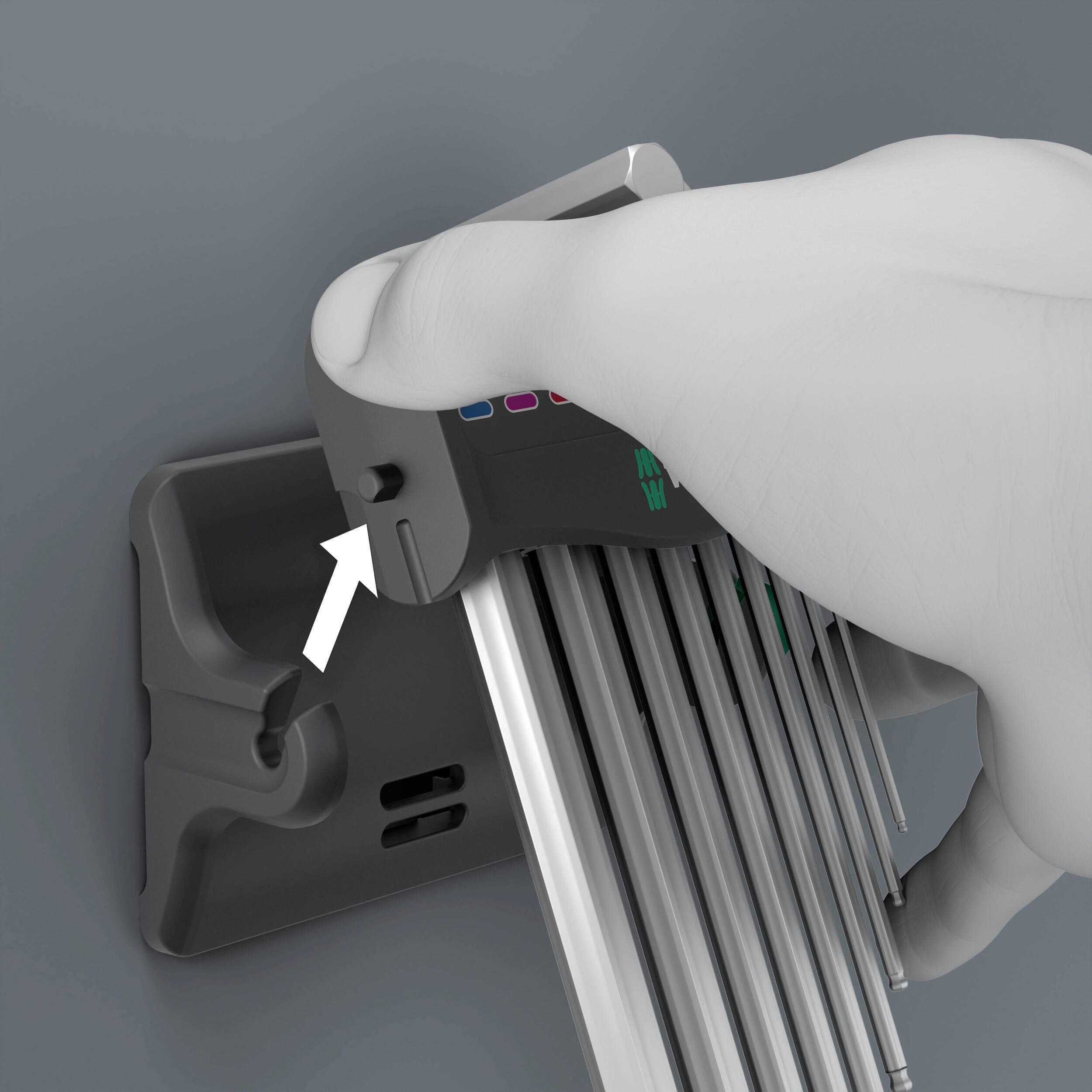 Eine Hand drückt auf einen Knopf an einem Gerät mit langen, parallelen Streben. Ein Pfeil zeigt auf die Stelle, die gedrückt wird.