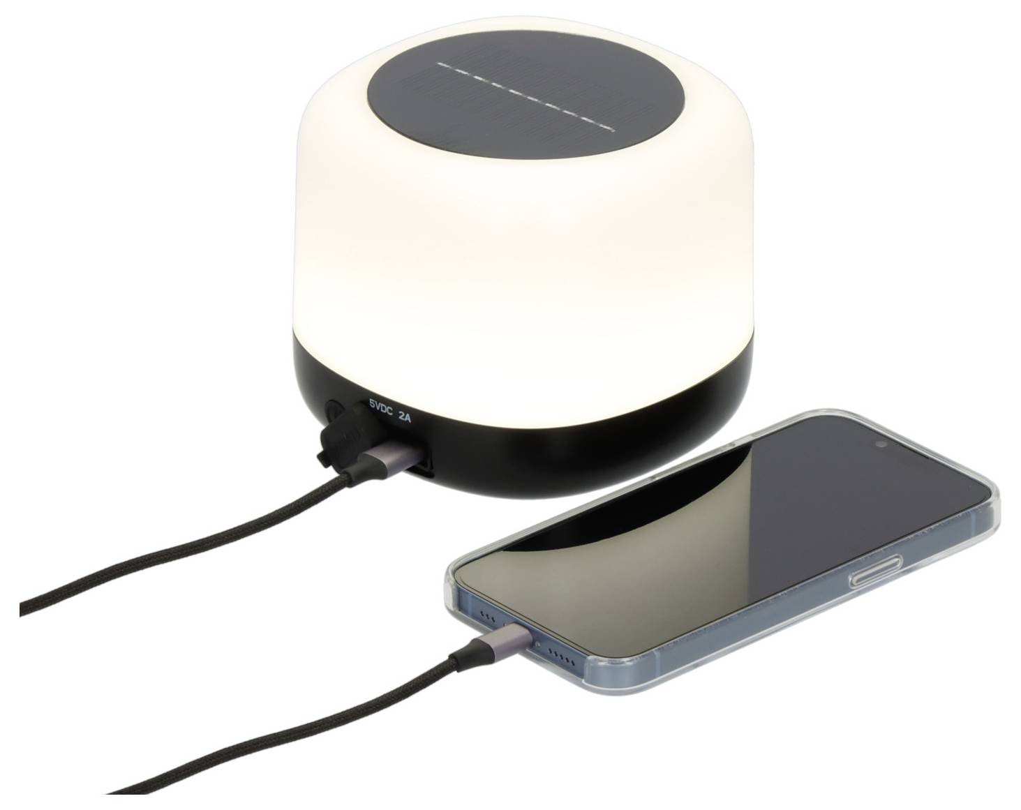 Kabellose Ladenlampe leuchtet weiß, während ein Smartphone per Kabel auf weißem Hintergrund aufgeladen wird.