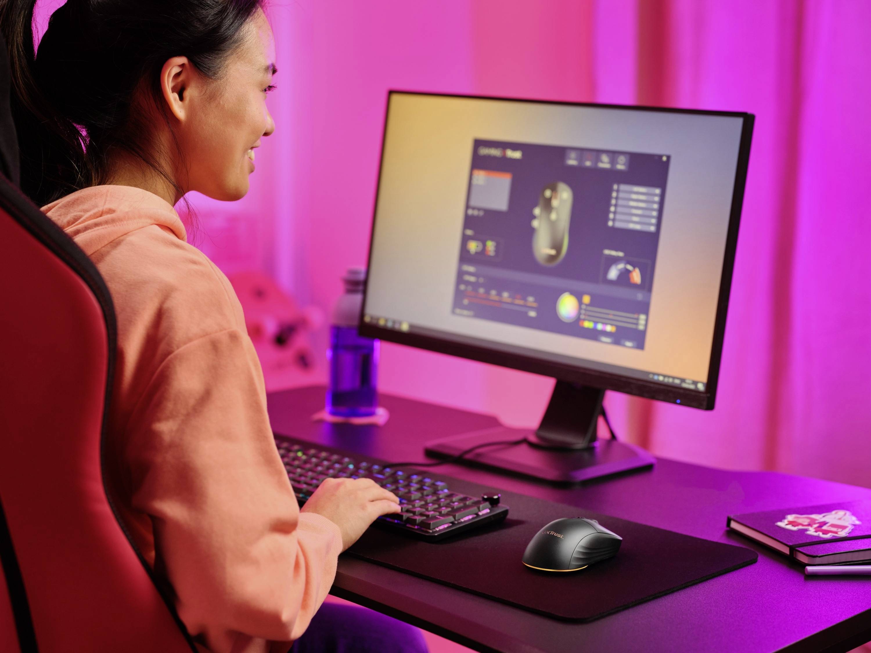 Eine Frau arbeitet an einem Schreibtisch mit einem Computer, auf dem ein Programm zur Anpassung von Computermauseinstellungen geöffnet ist.