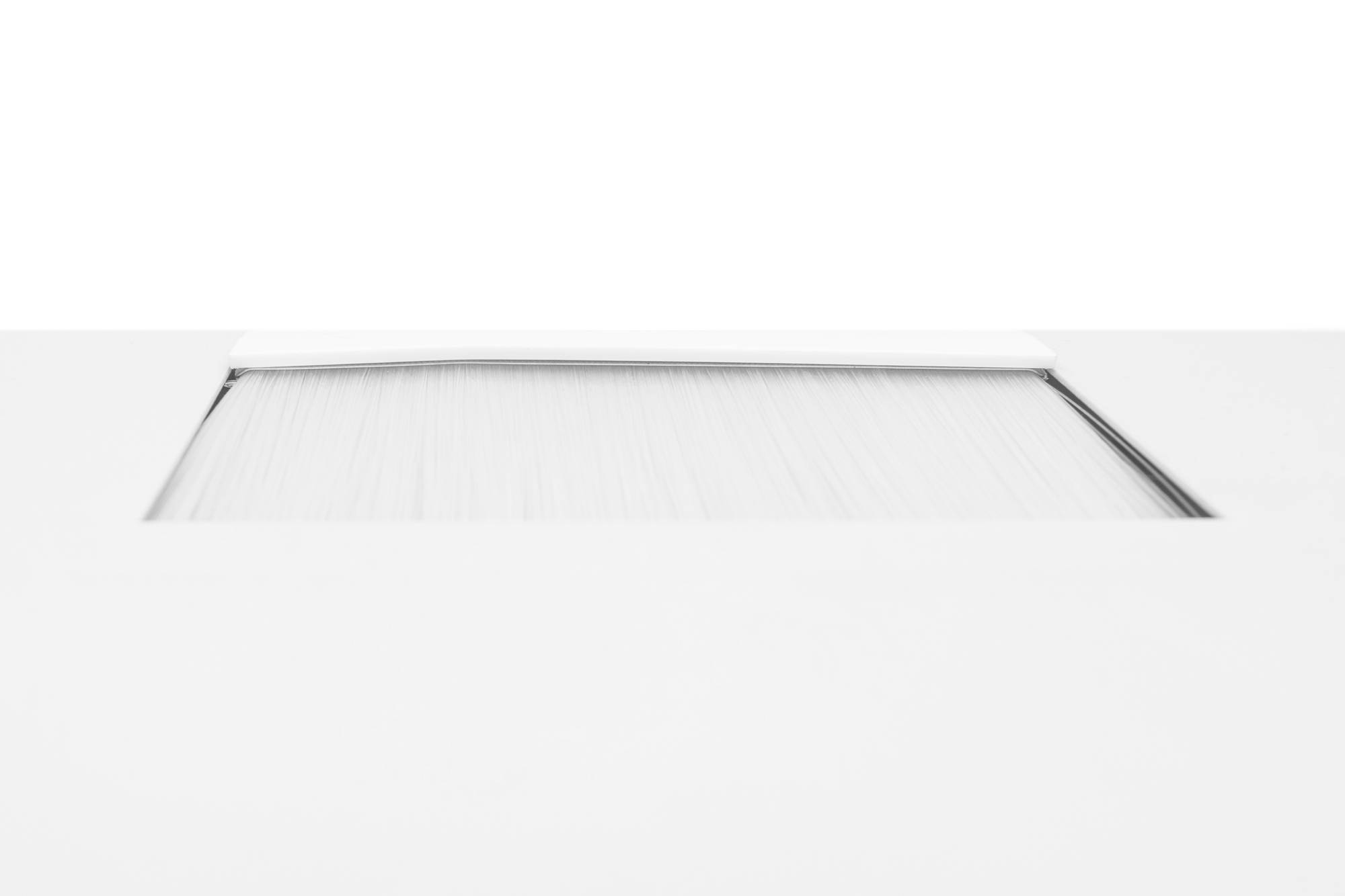 Ein rechteckiger, leicht geöffneten Schlitz in einer glatten, weißen Oberfläche.