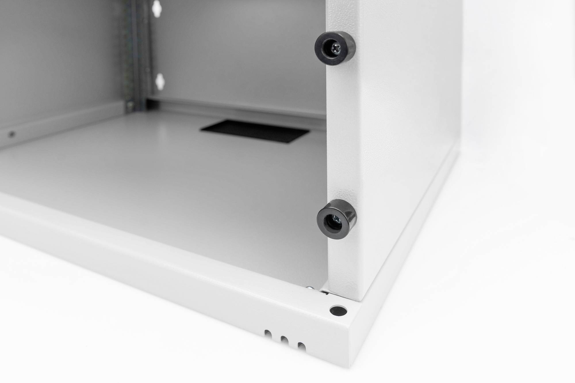 Eckansicht eines weißen Metallschranks mit sichtbaren Schrauben und Belüftungsschlitzen, Teilansicht der Innenstruktur.