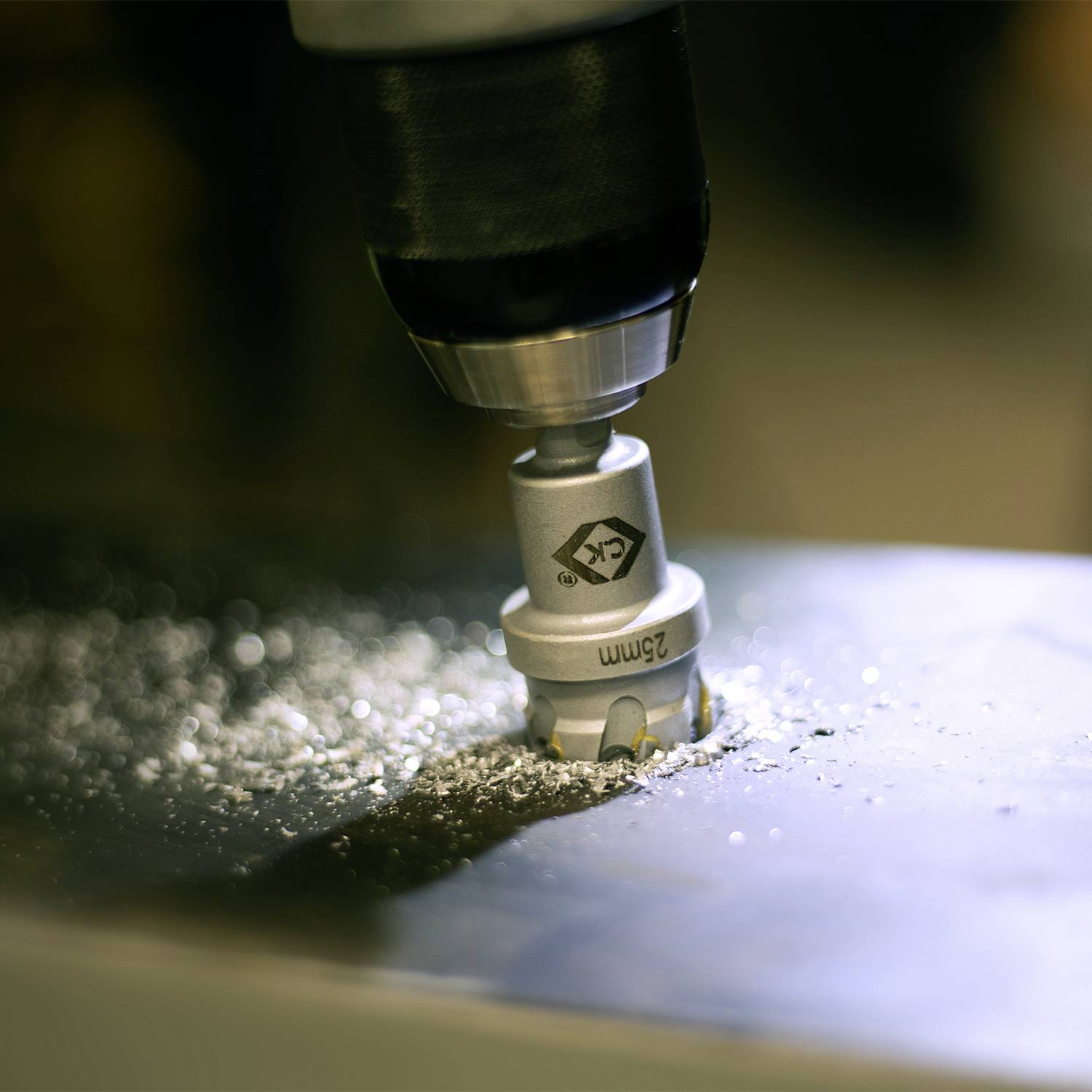 Ein Bohrer durchdringt eine Metallplatte, erzeugt Metallspäne und Funken. Fokus auf präzise Arbeit in einer Werkstattumgebung.