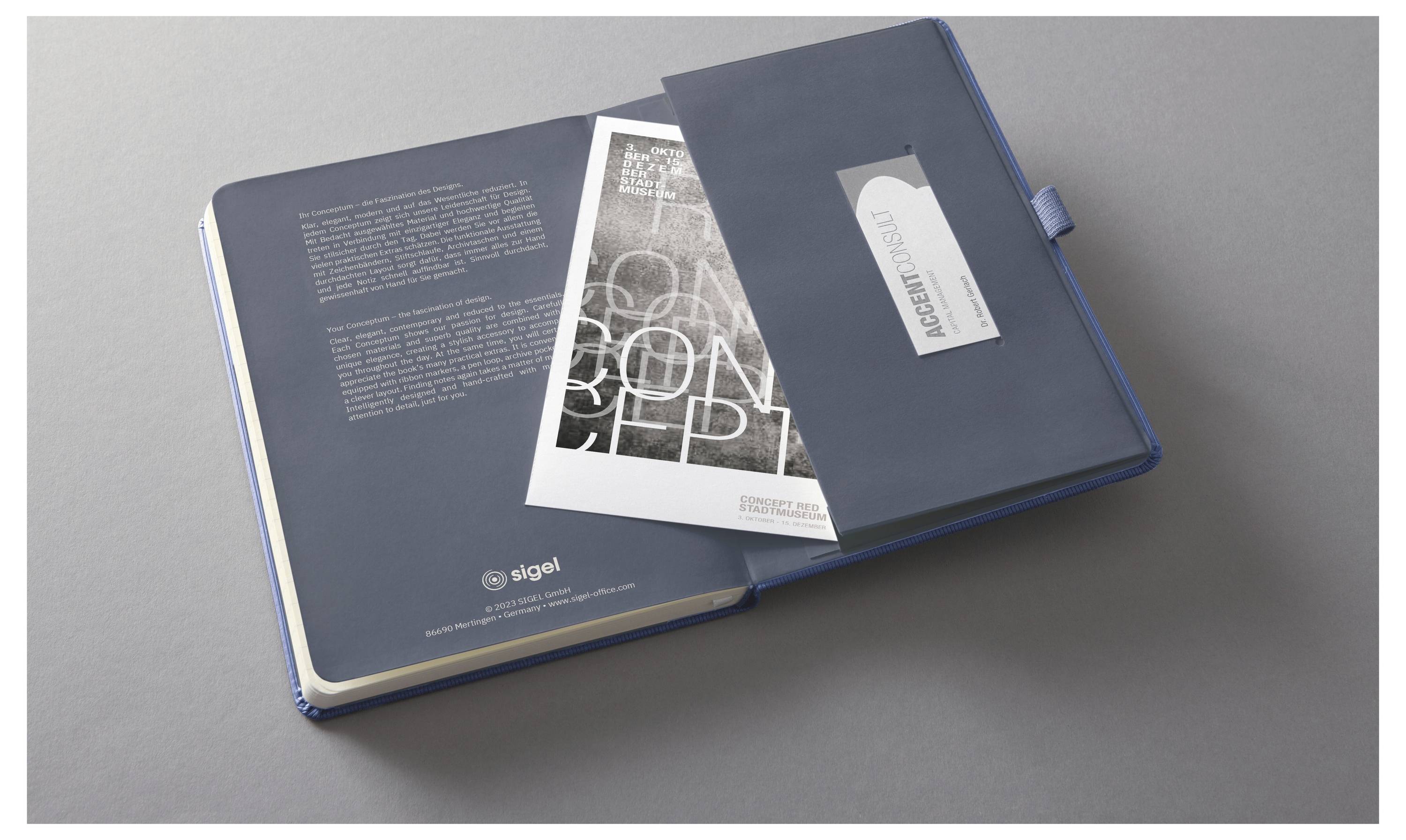 Offenes blaues Präsentationsportfolio mit einer Broschüre und einem Booklet im Inneren, gezeigt auf einer grauen Oberfläche.