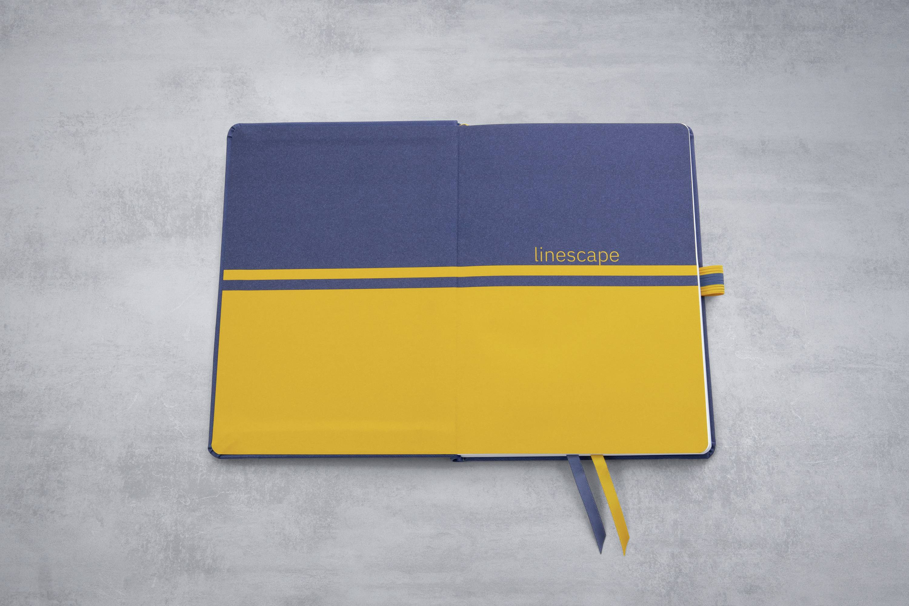 Notizbuch mit blauem und gelbem Cover, geöffnet auf einer Doppelseite. Das Wort 'linescape' ist auf das Cover gedruckt.