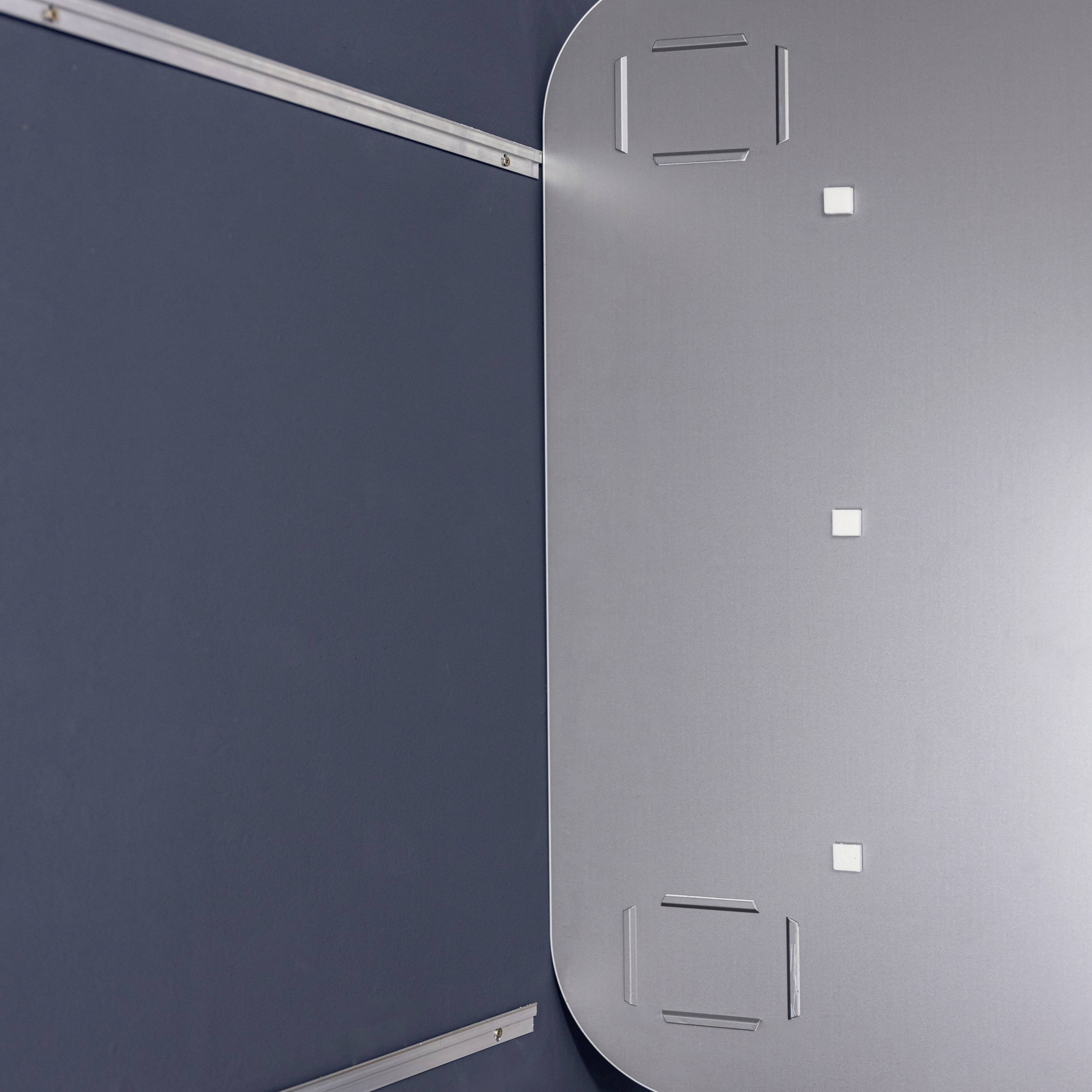 Graue Metallfläche mit rechteckiger Form, vier abgerundete Ecken und mehreren quadratischen Vertiefungen; Teil einer modern gestalteten Umgebung.