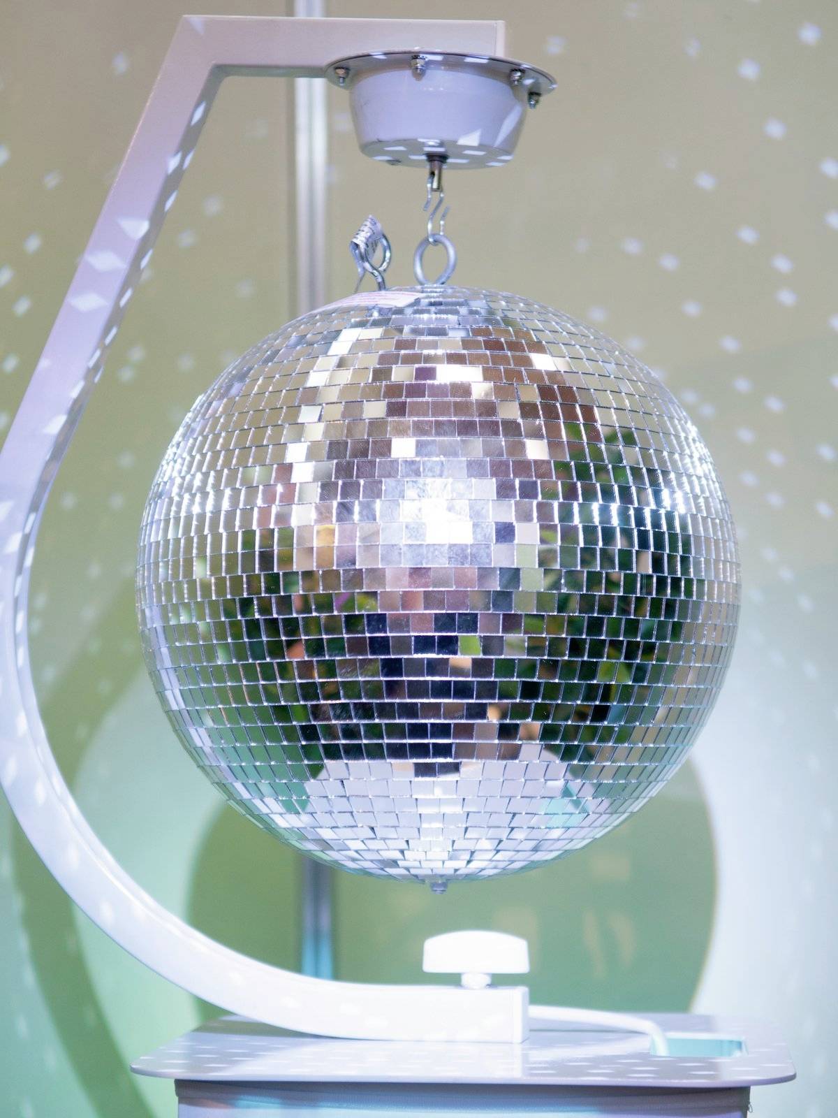 Eine spiegelnde Discokugel hängt an einer Halterung, reflektiert Lichtpunkte und erzeugt eine lebendige Atmosphäre im Raum.