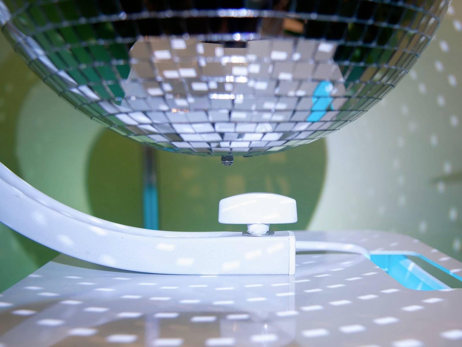 Eine spiegelnde Discokugel wirft Lichtpunkte auf eine Wand. Die Lichtreflexionen erzeugen eine dynamische Atmosphäre.