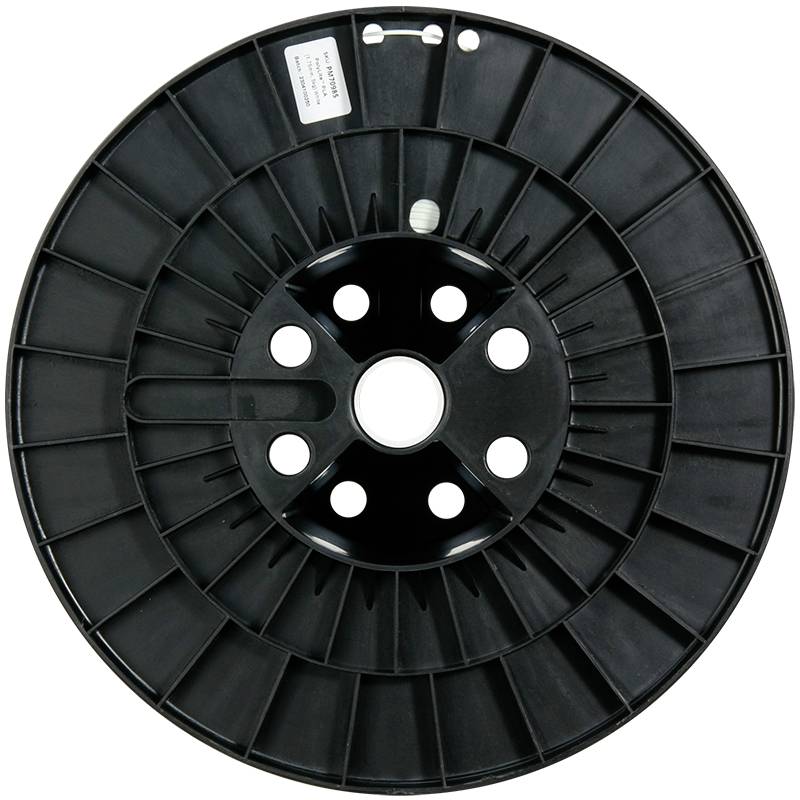 Eine leere, schwarze Kabelspule mit mehreren Löchern im Rand, fotografiert von oben. Sie hat einen Aufkleber mit einem Text auf der Seite.