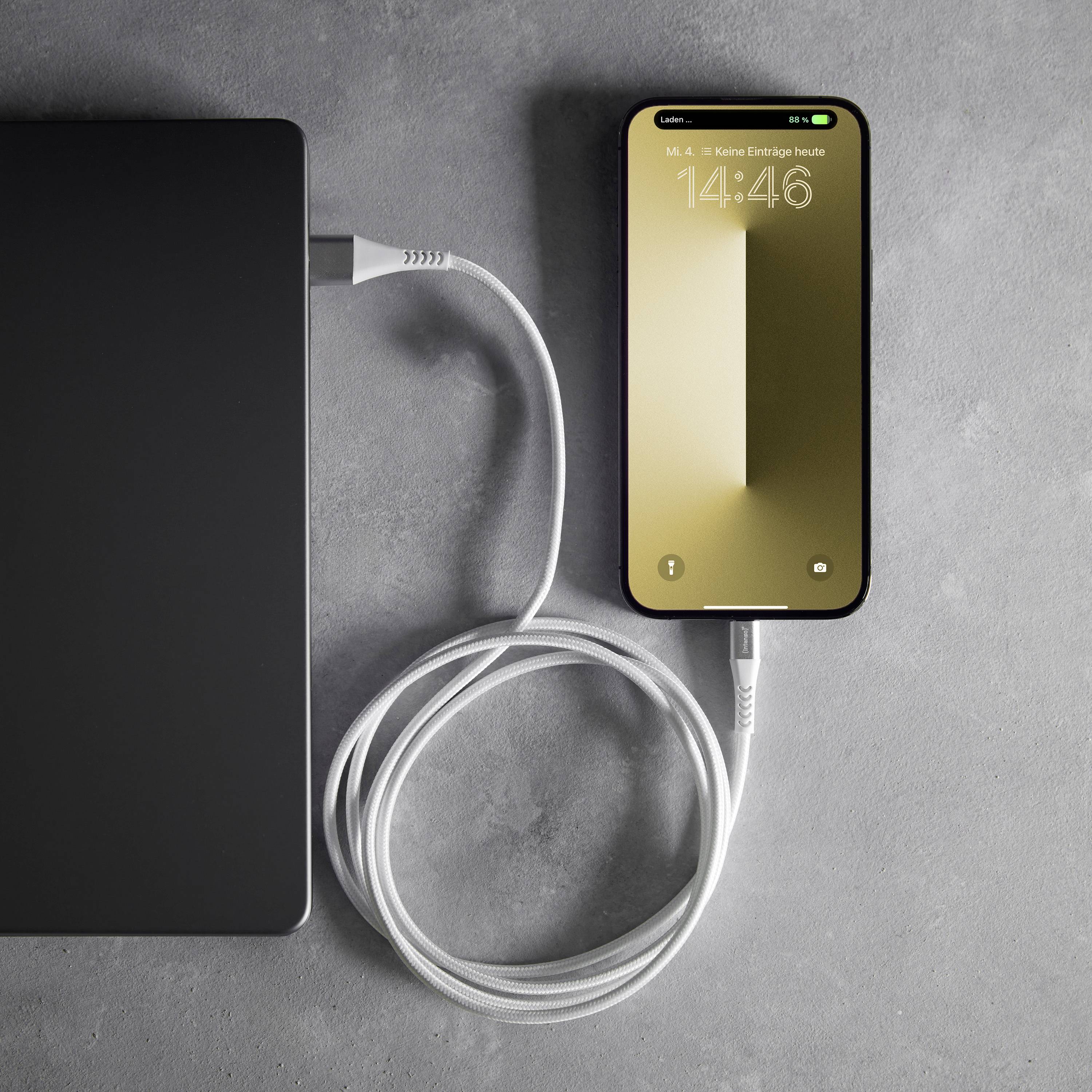 Ein Smartphone lädt über ein angeschlossenes Kabel von einer schwarzen Powerbank auf einem grauen Hintergrund.