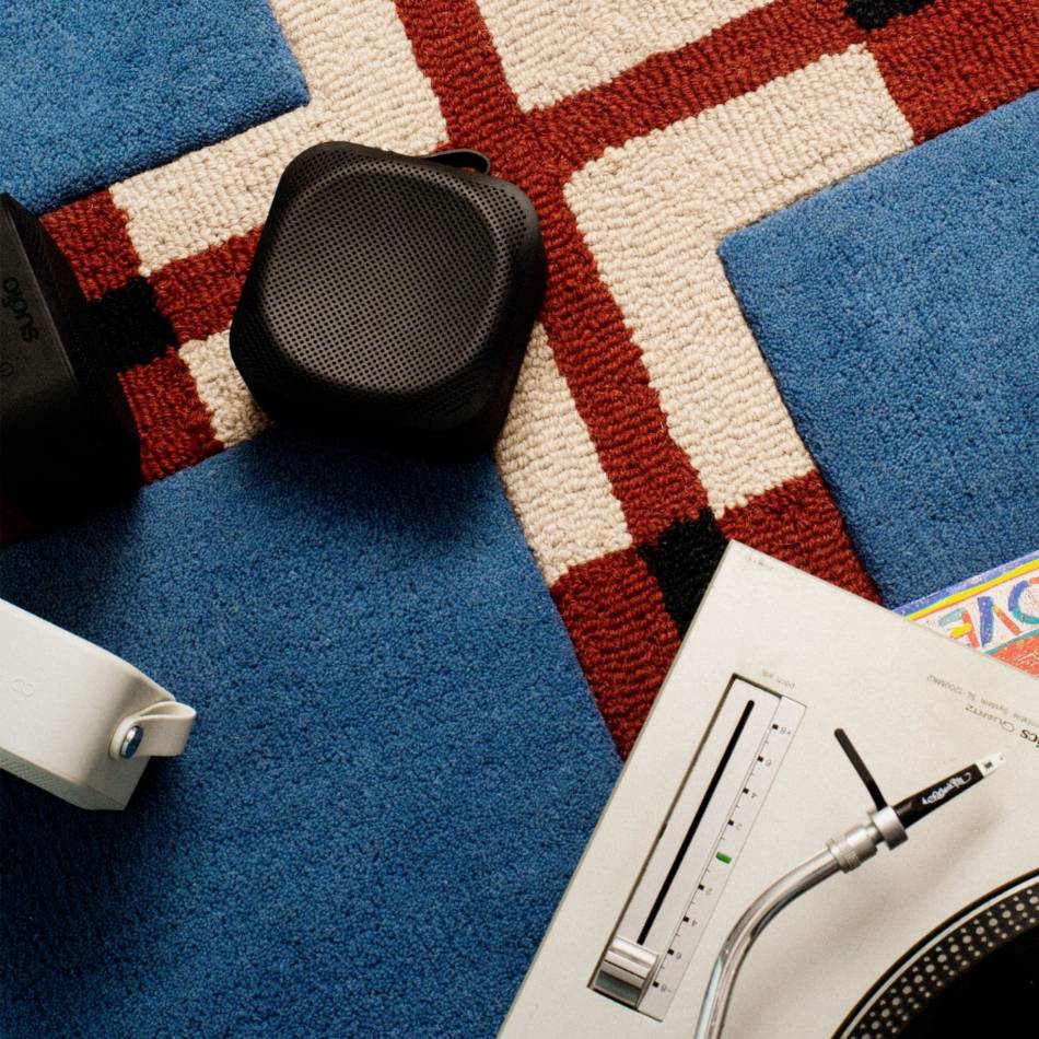 Eine schwarze Lautsprecherbox und ein Plattenspieler mit einem blauen Teppich im Hintergrund.