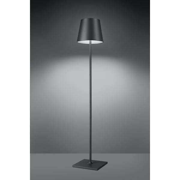 Stehlampe mit modernen, grauem Schirm, leuchtet in dunklem Raum, gleichmäßiges Licht auf Wand werfend, minimalistisch und elegant.