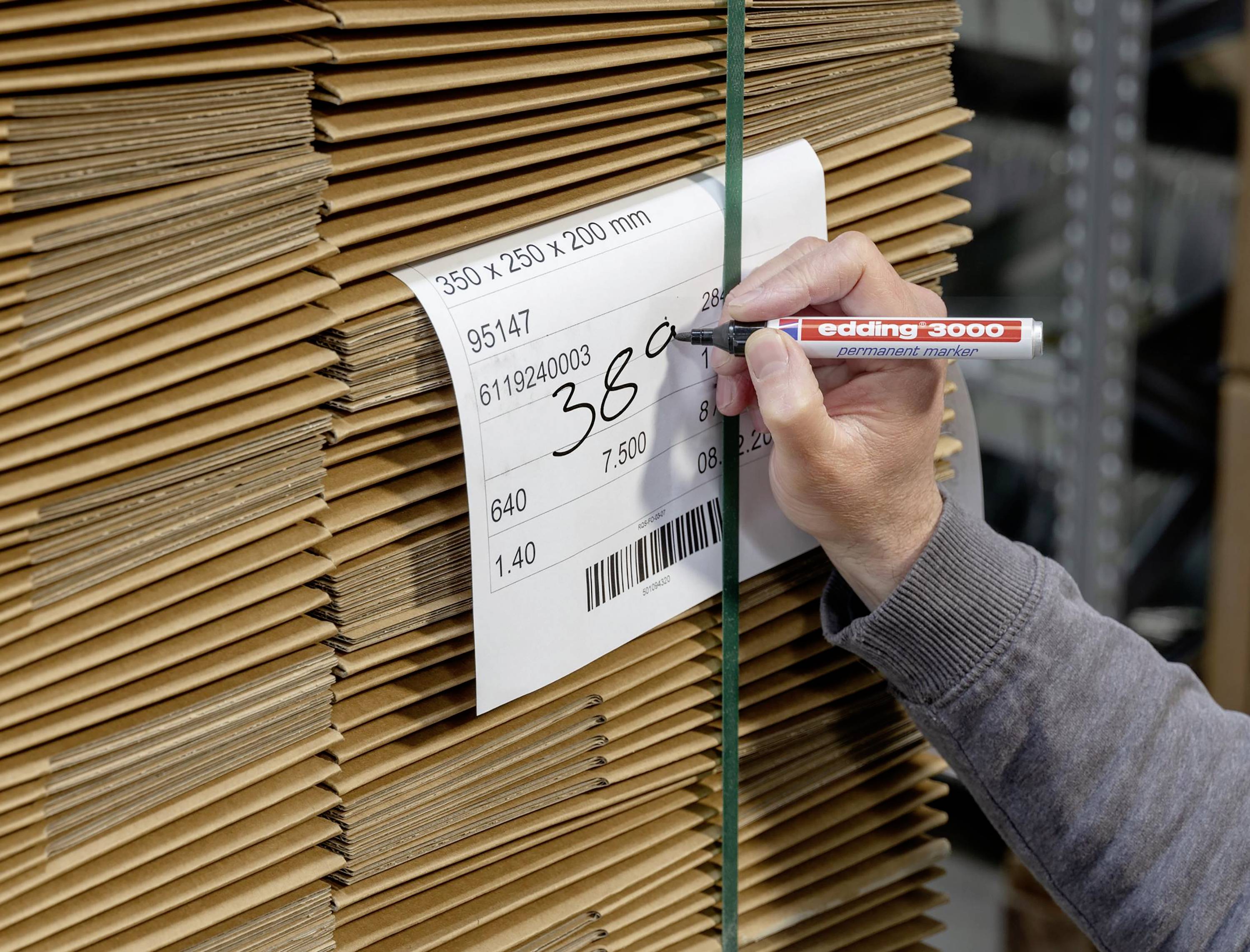Eine Person beschriftet ein Etikett auf einem Stapel Kartons mit der Aufschrift '380'.
