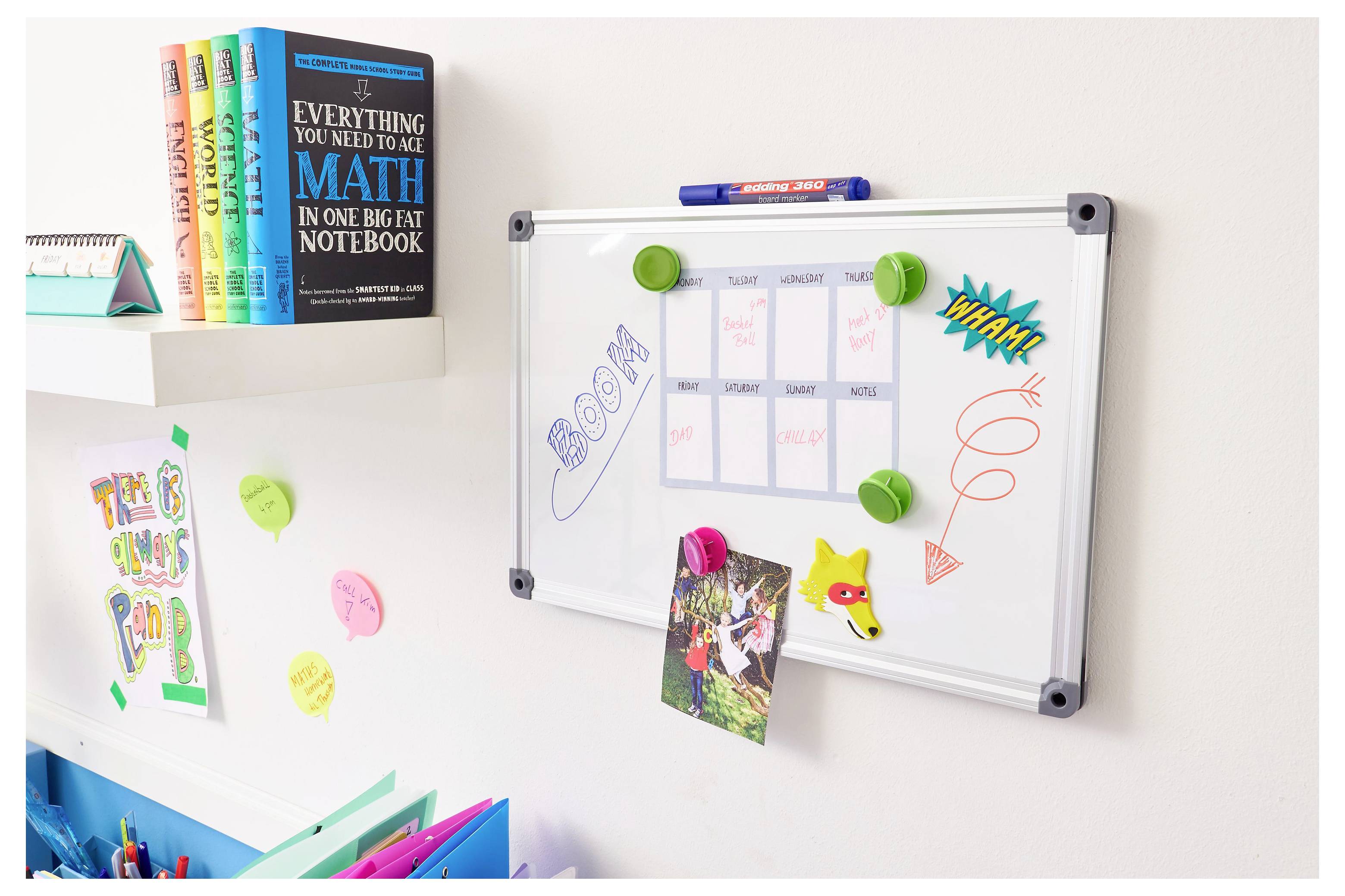 Ecke zum Lernen für Kinder mit einem Whiteboard, das einen Wochenplan zeigt, Kritzeleien und angeheftete Fotos, neben Bücherregalen und Notizen.