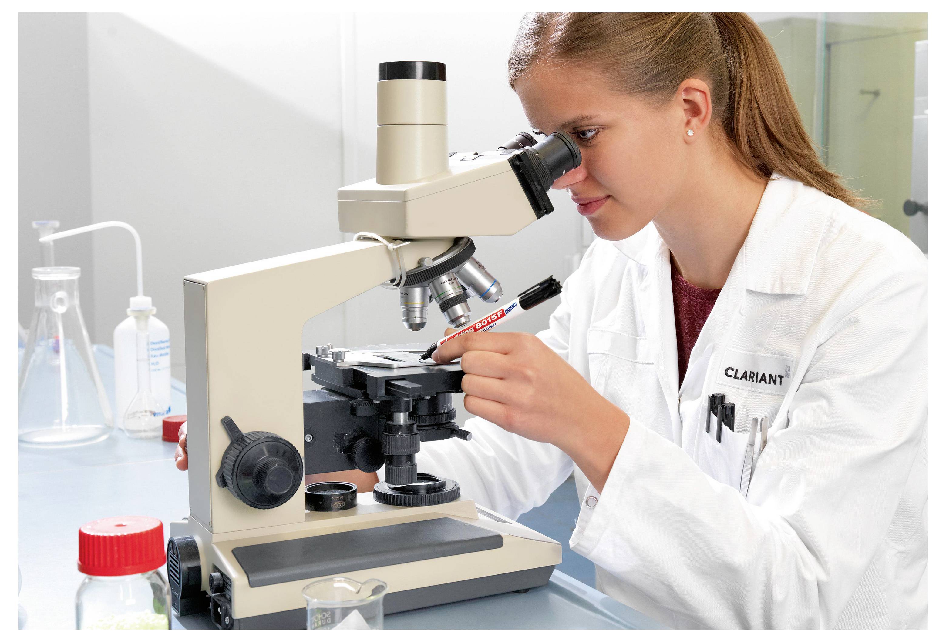 Wissenschaftler im Laborkittel untersucht eine Probe unter einem Mikroskop in einem Labor.