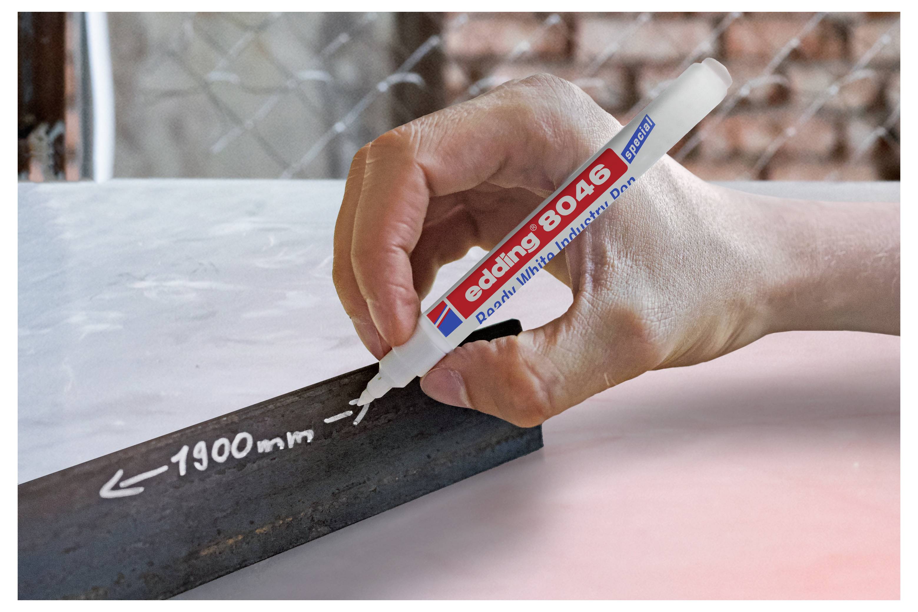 Handschrift auf einem schwarzen Streifen mit einem weißen Edding 8046 Lackmarker, beschriftet mit „1900 mm" mit Pfeilen, auf einer hellen Oberfläche.