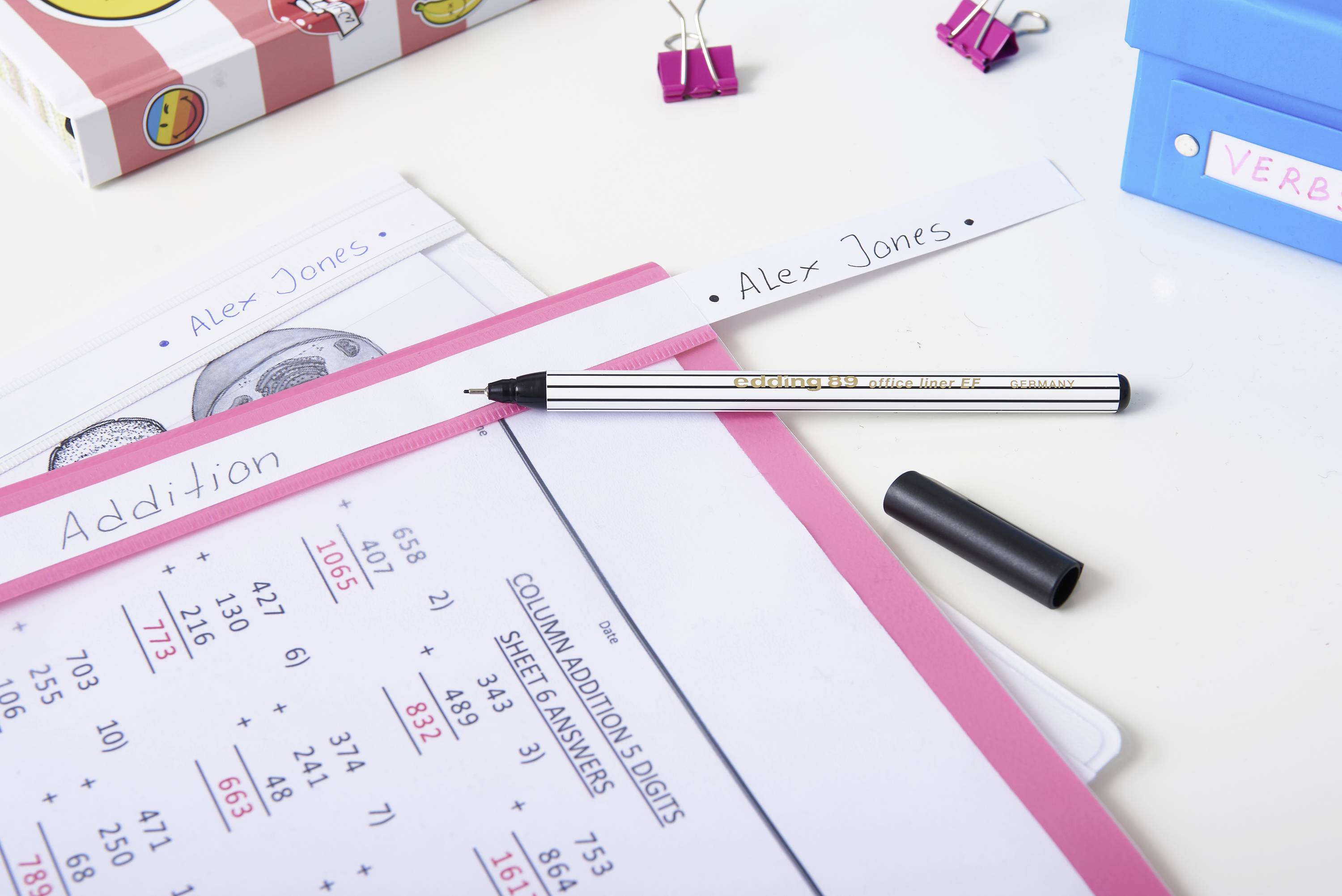 Ein Schreibtisch mit einem Arbeitsblatt 'Addition'. Ein Stift liegt daneben und Ordner sind im Hintergrund.