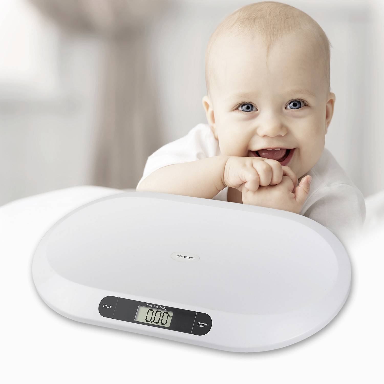 Ein lächelndes Baby sitzt hinter einer digitalen Babywaage, die ein Gewicht von '0.00 kg' anzeigt.
