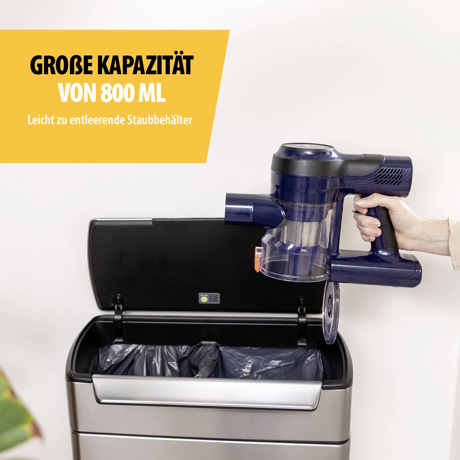 Kabelloser Staubsauger, der über einem offenen Mülleimer entleert wird. Text auf Gelb: 'Große Kapazität von 800 ml'.