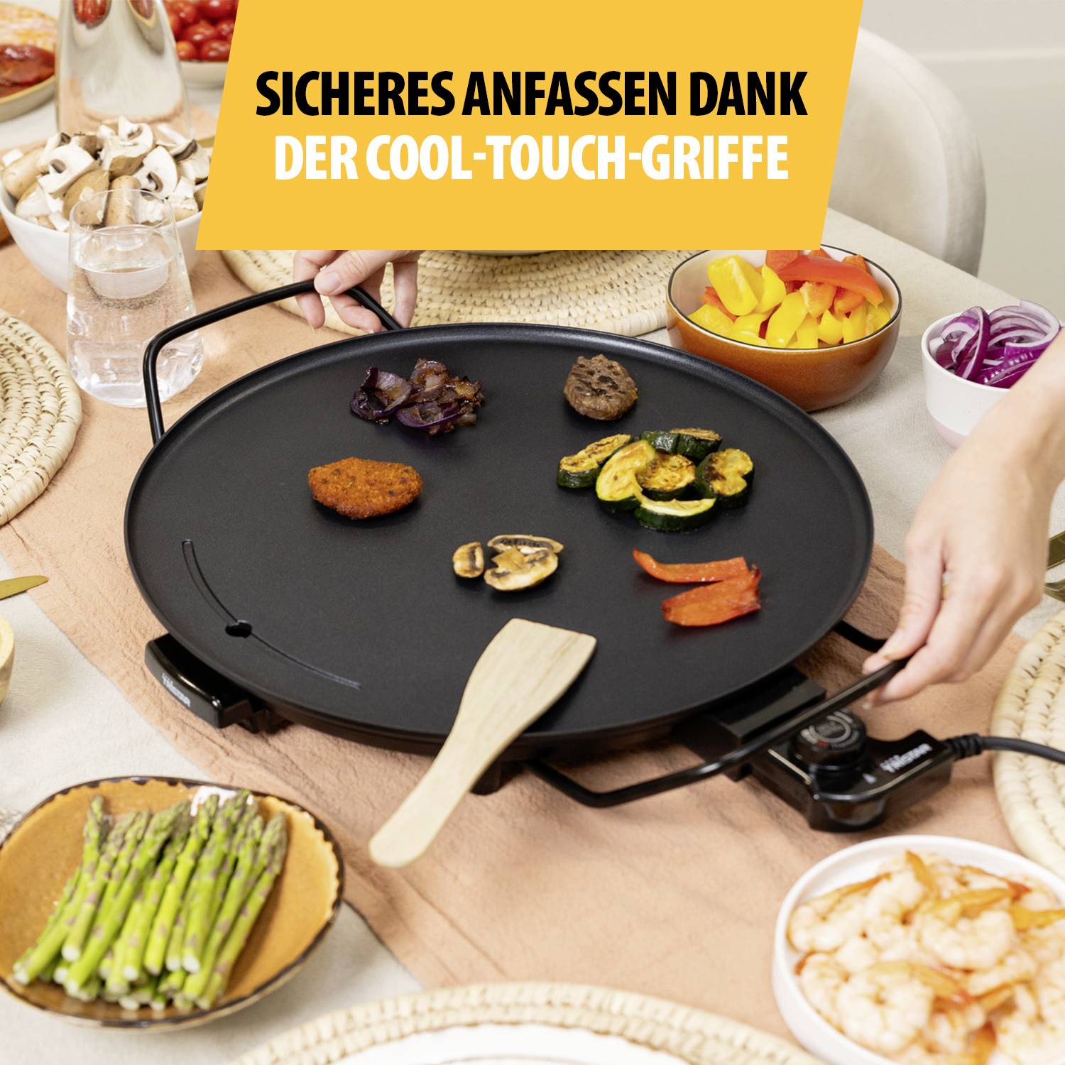 Eine elektrische Grillplatte mit Speisen wie Gemüse, Fleischbällchen und Garnelen. Text oben: 'Sicheres Anfassen dank der Cool-Touch-Griffe'.