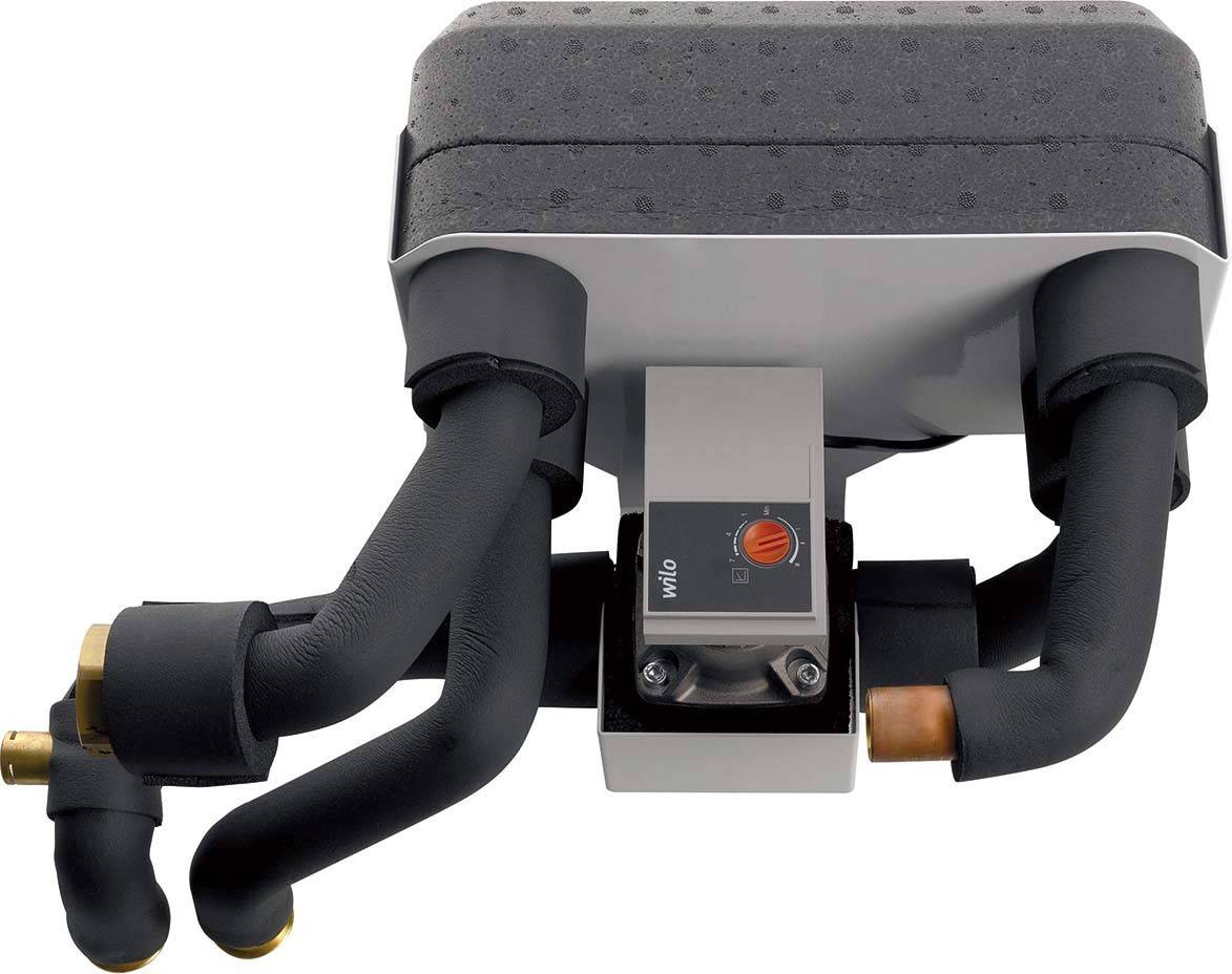 Das Bild zeigt eine Pumpeninstallation mit schwarzen Rohren. In der Mitte befindet sich ein Steuerkasten mit einem roten Einstellungsknopf.