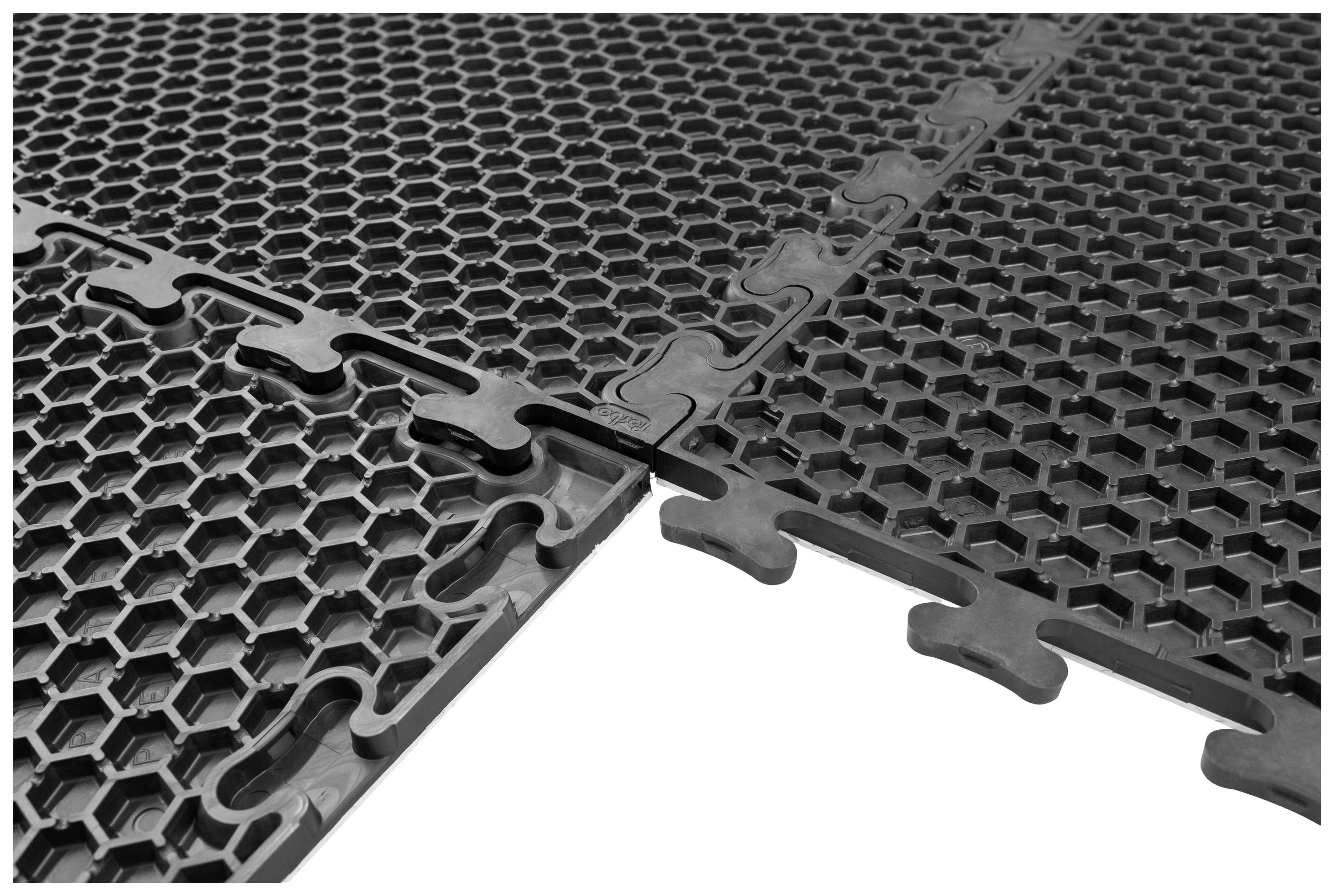 Schwarze ineinandergreifende Bodenmatten mit wabenförmigem Muster. Sie sind teilweise verbunden und liegen auf einer ebenen Fläche.