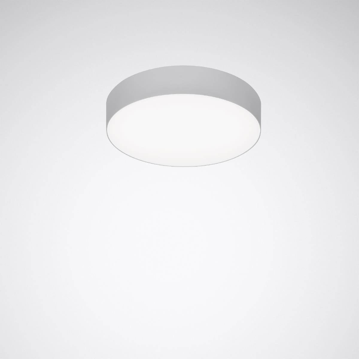 Eine runde, schlichte Deckenleuchte leuchtet in einem minimalistischen Raum. Sie strahlt gleichmäßiges, weißes Licht aus.