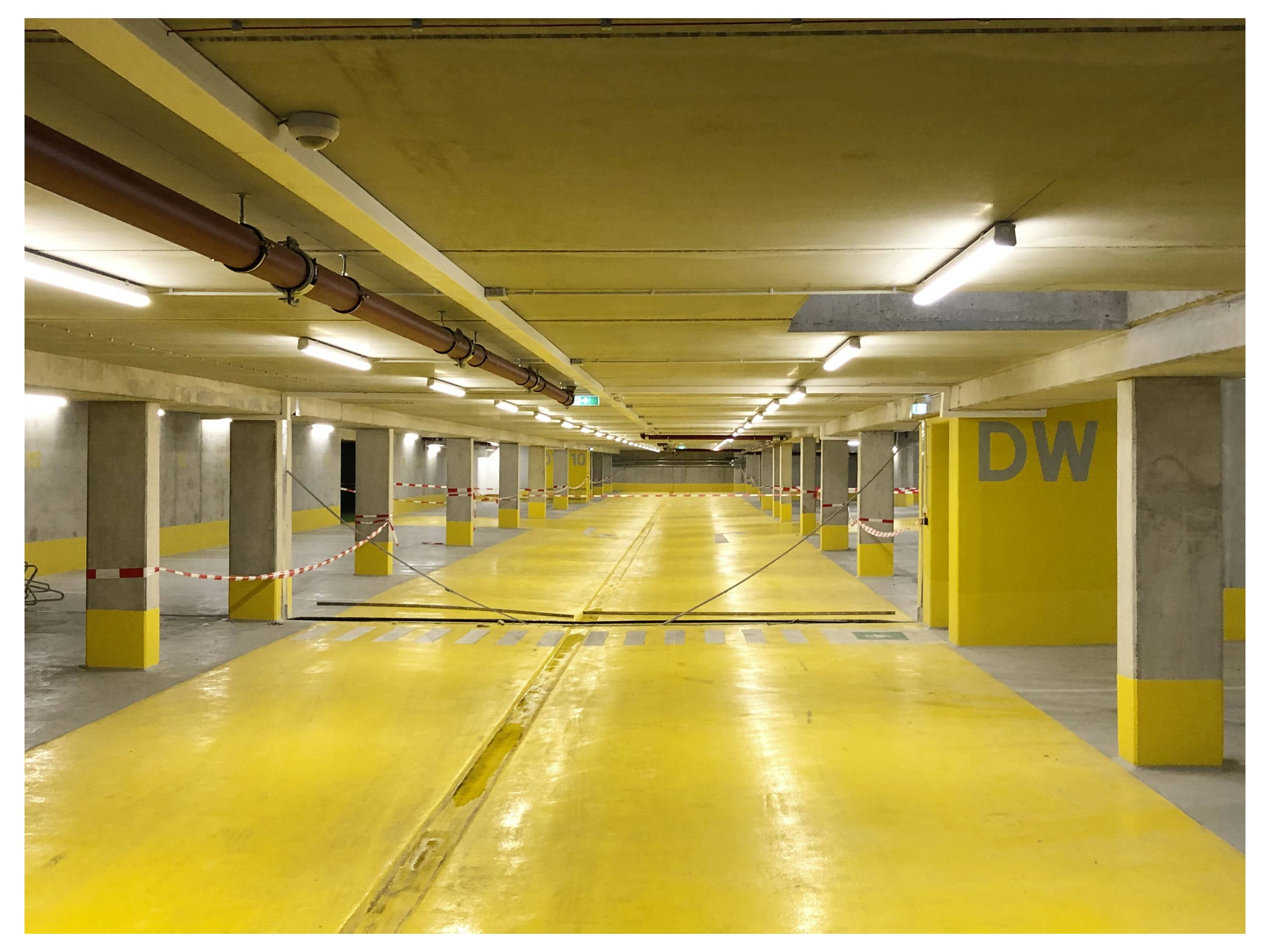 Flur in einem Gebäude mit mehreren geschlossenen Türen, die nummeriert sind, wobei die Tür mit der Nummer '522' im Fokus steht. An der Decke sind sichtbare Versorgungsleitungen und Beleuchtung zu sehen.