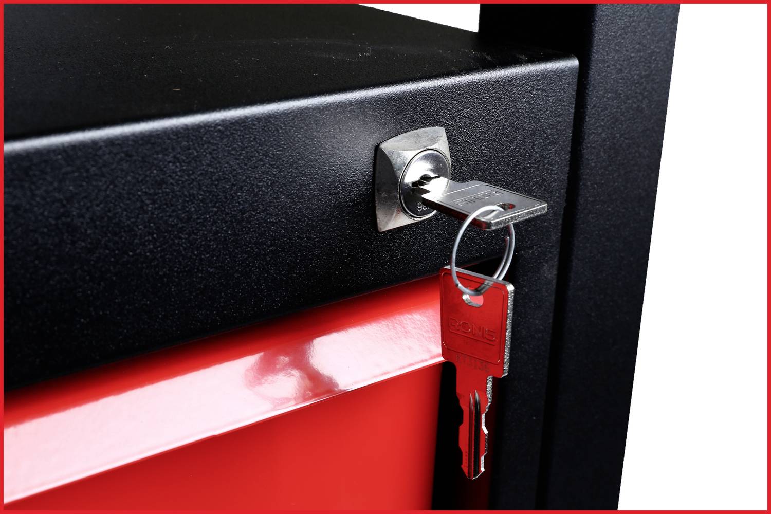 Ein schwarzes Möbelstück mit einem silbernen Schlüssel im Schloss und einem roten Schlüsselanhänger hängt an einem Schlüsselsatz.