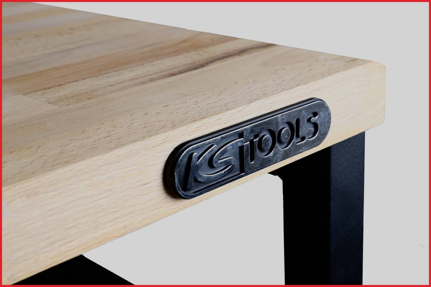 Holztischplatte mit Metallrahmen. Auf der Tischkante ist ein Metallschild mit der Aufschrift 'KS TOOLS' befestigt.