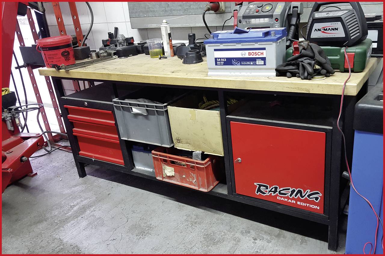 Werkbank mit Schubladen und Regalflächen, gefüllt mit Werkzeugen, einer Batterie und Ausrüstungen. Beschriftung 'Racing Dakar Edition'.