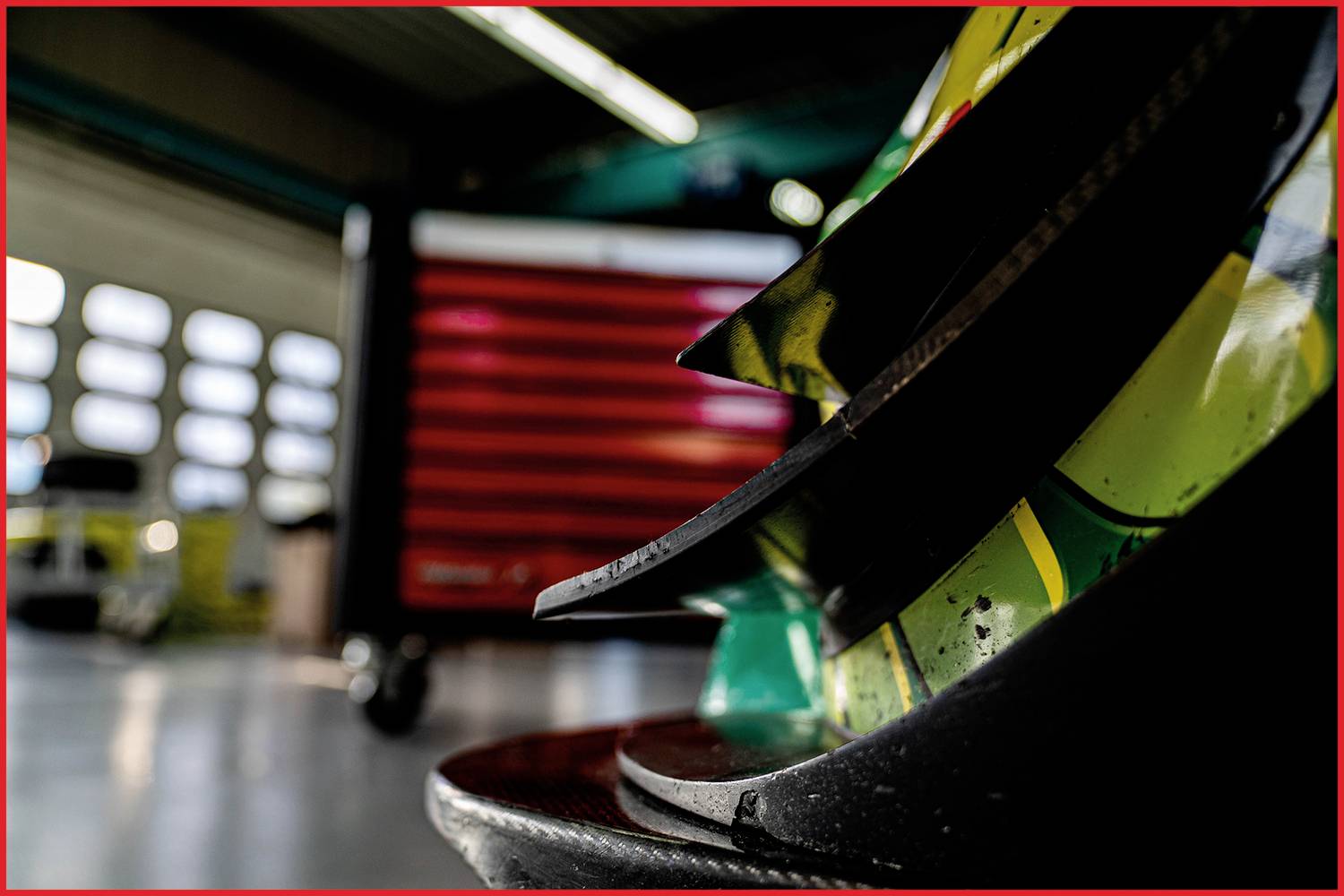 Nahaufnahme eines Autoteils in einer Werkstatt, im Hintergrund ist unscharf eine rote Werkzeugkiste erkennbar.