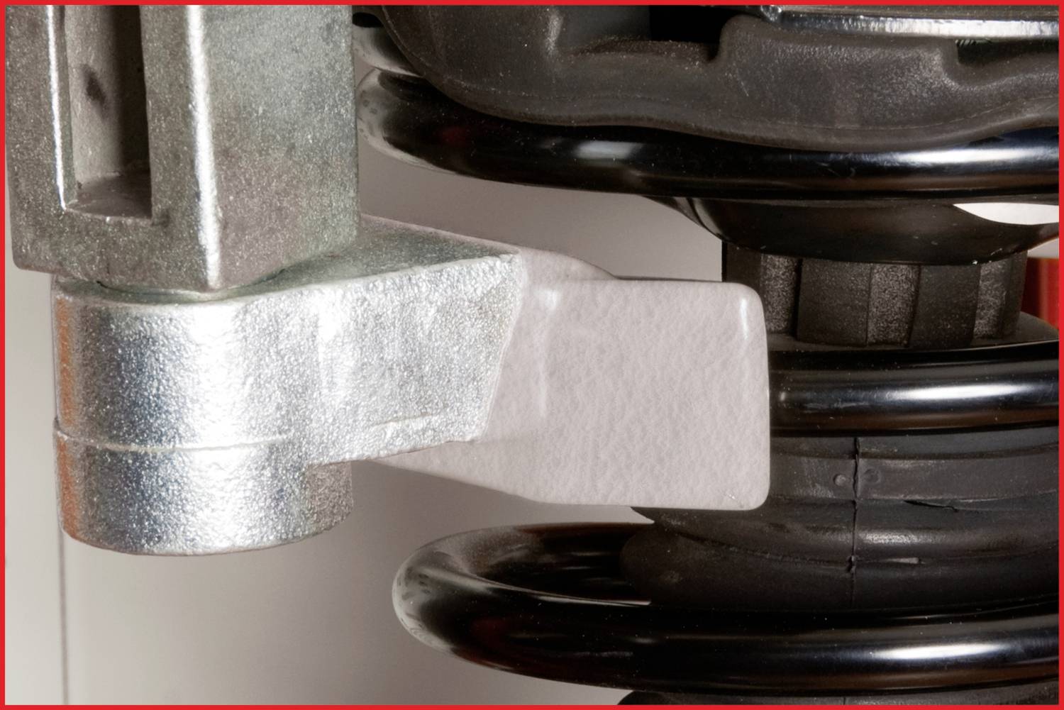 Nahaufnahme eines Autostoßdämpfers mit metallischen und plastischen Komponenten. Der Stoßdämpfer zeigt Federn und Halterungsteile.