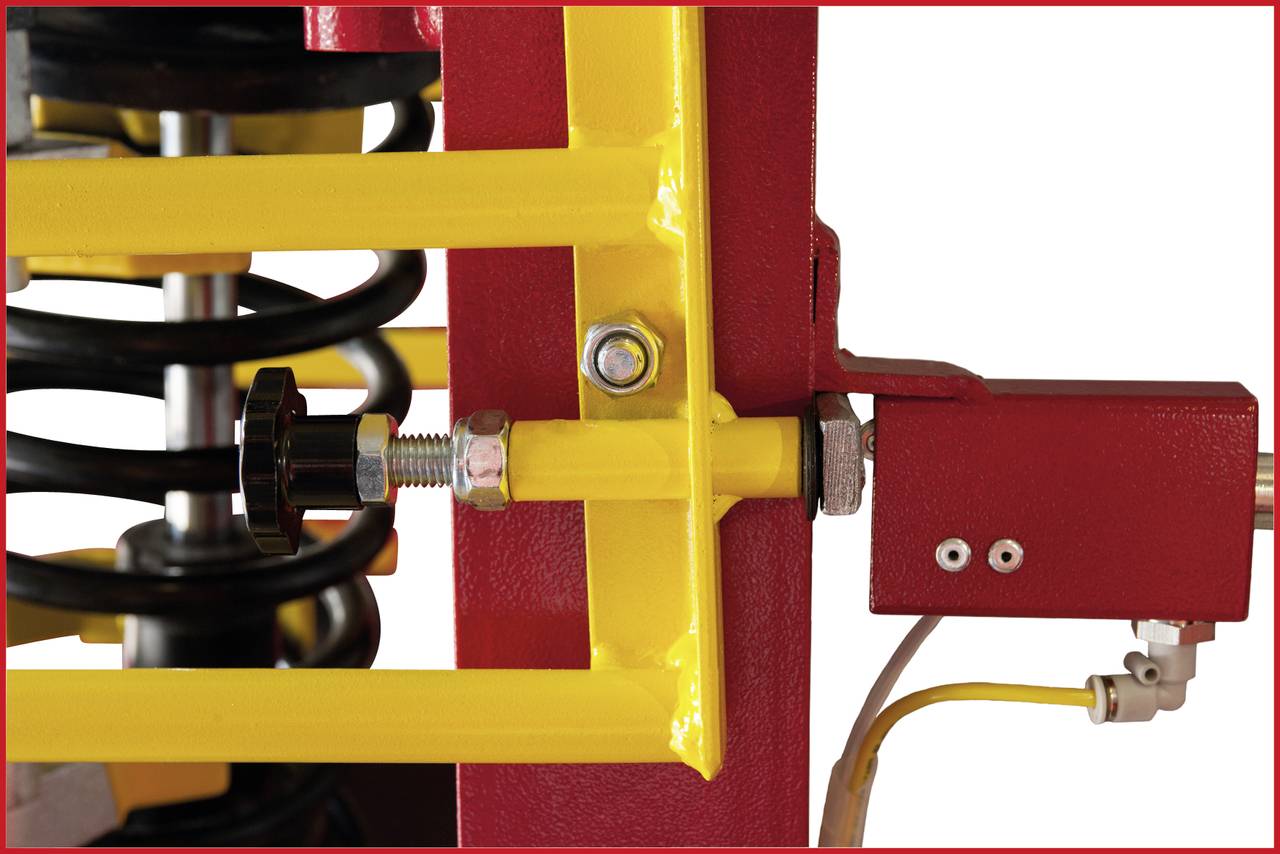Nahaufnahme einer gelben Rahmenstruktur mit schwarzen Federn und rotem Hydraulikelement. Mechanische Teile für Fahrzeugtechnik.