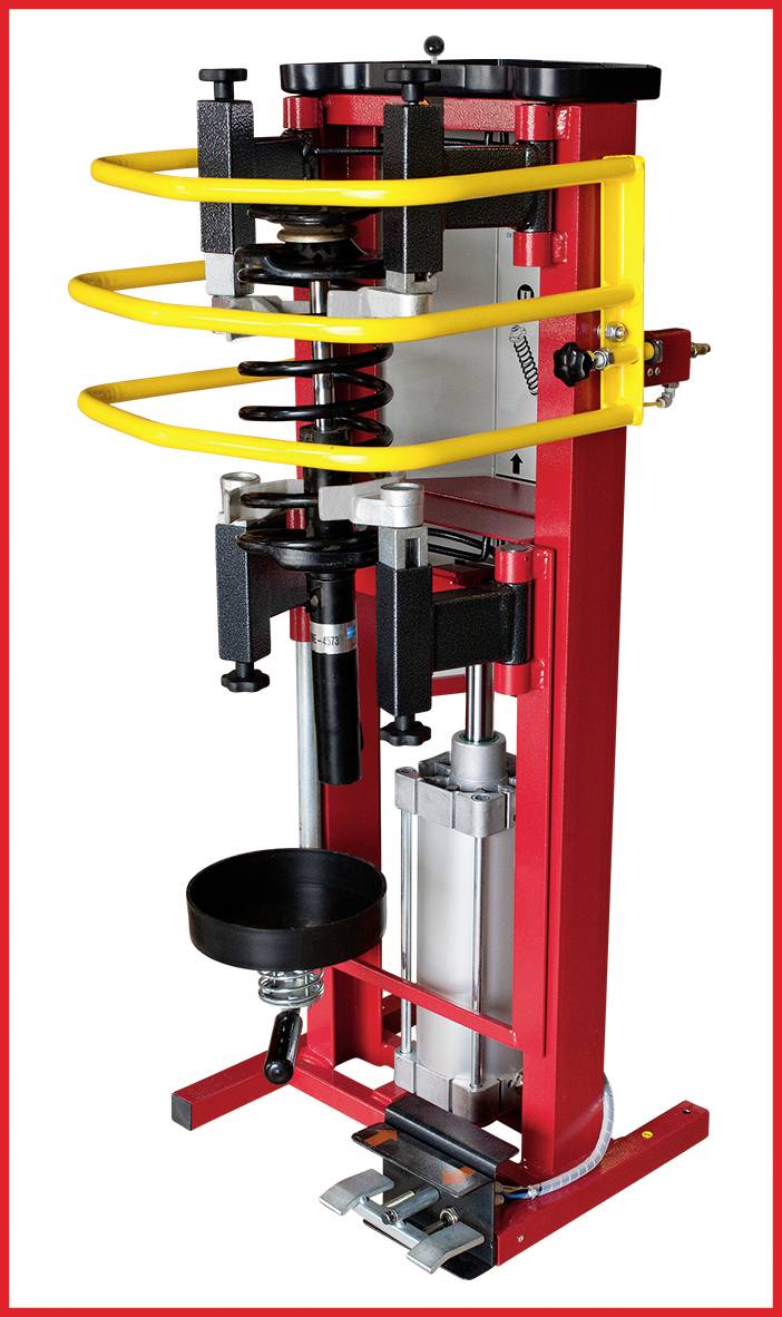 Rote und gelbe Maschine zur Montage und Demontage von Federn bei Fahrzeugaufhängungen. Sie hat eine vertikale Struktur mit verschiedenen Hebeln und Halterungen.