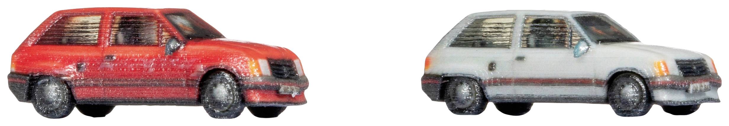 Zwei Miniaturautos, eines in Rot, das andere in Grau, nebeneinander vor weißem Hintergrund.