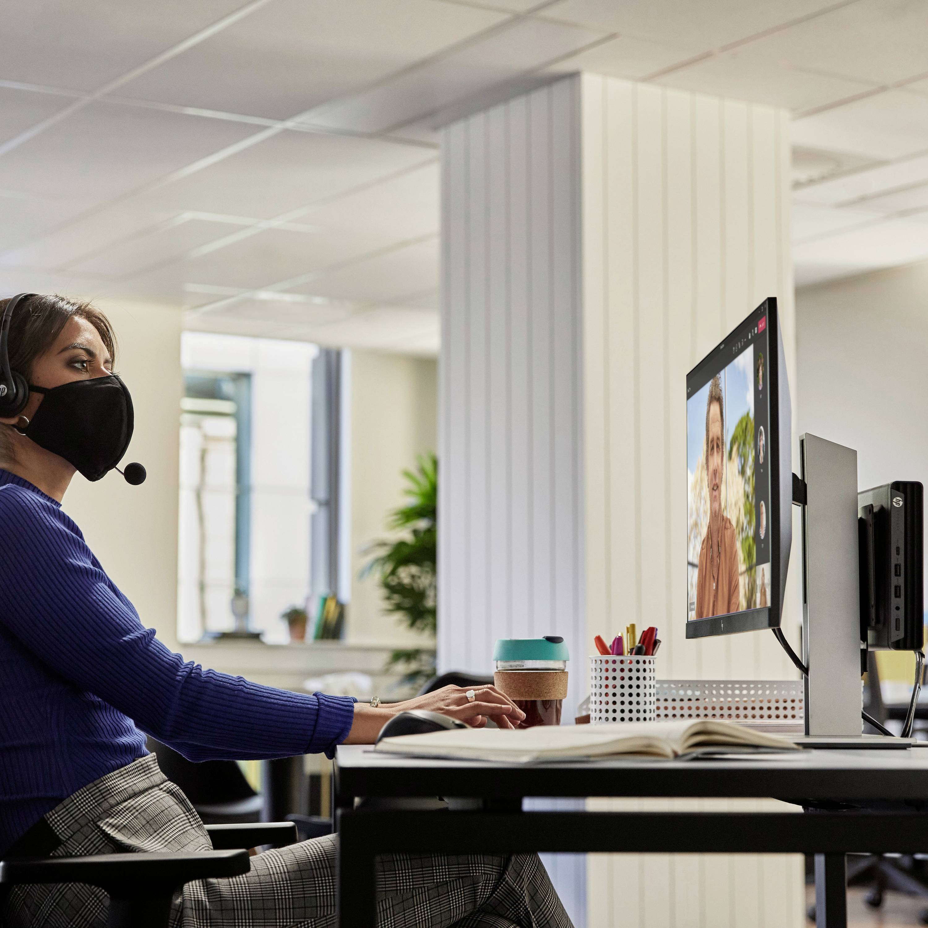 Eine Frau sitzt an einem Schreibtisch, trägt ein Headset und führt ein Videogespräch auf einem Computerbildschirm.