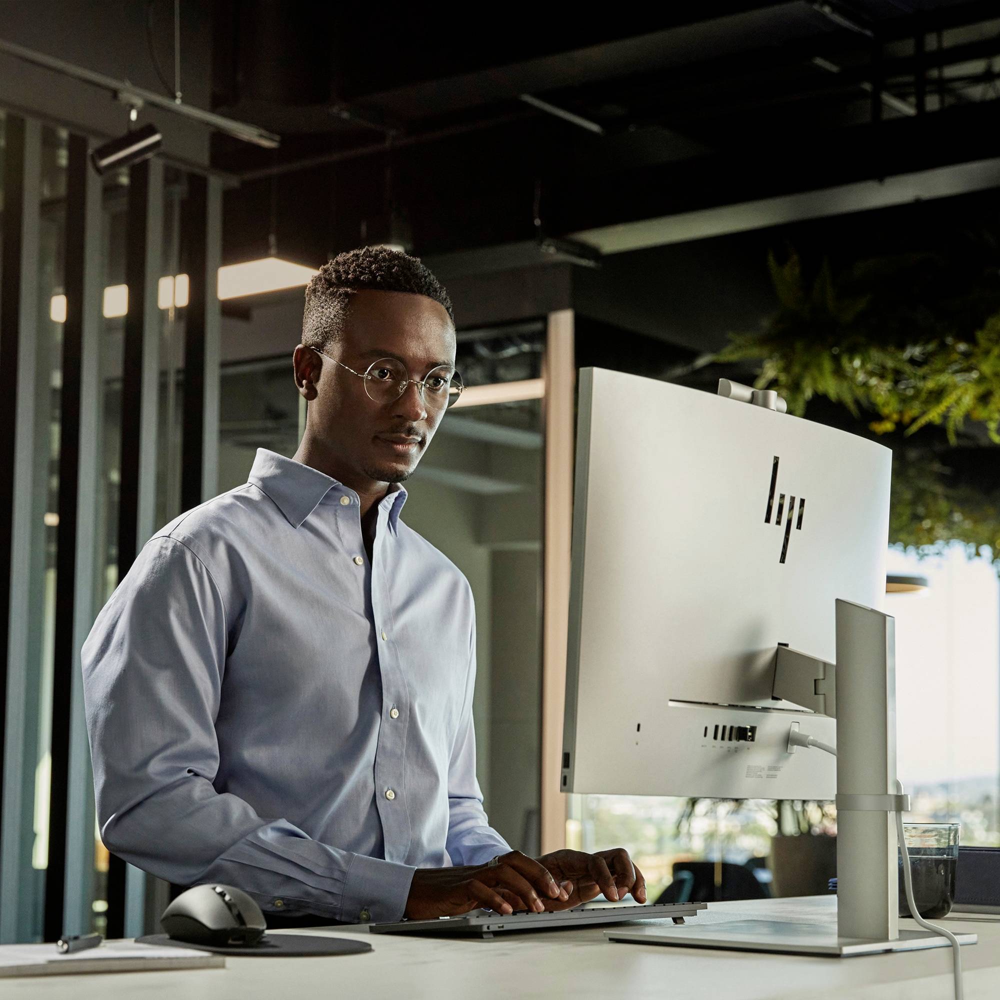 Eine Person arbeitet konzentriert an einem Computer in einem modernen Büro, mit Pflanzen im Hintergrund, die eine entspannte Atmosphäre schaffen.