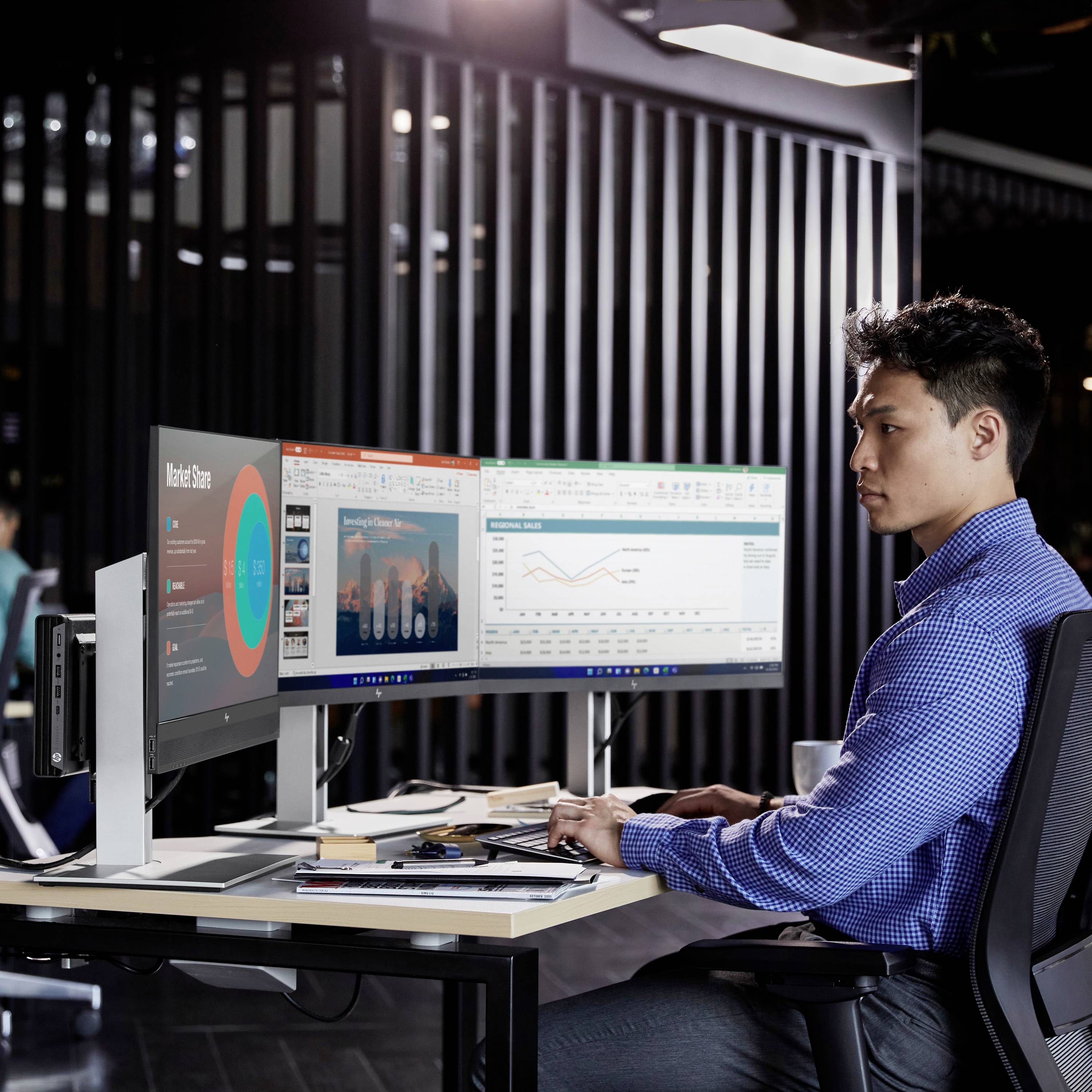 Ein Mann arbeitet an zwei Monitoren in einem modernen Büro. Auf den Bildschirmen sind Diagramme und Tabellen zu sehen, die Datenanalysen zeigen.