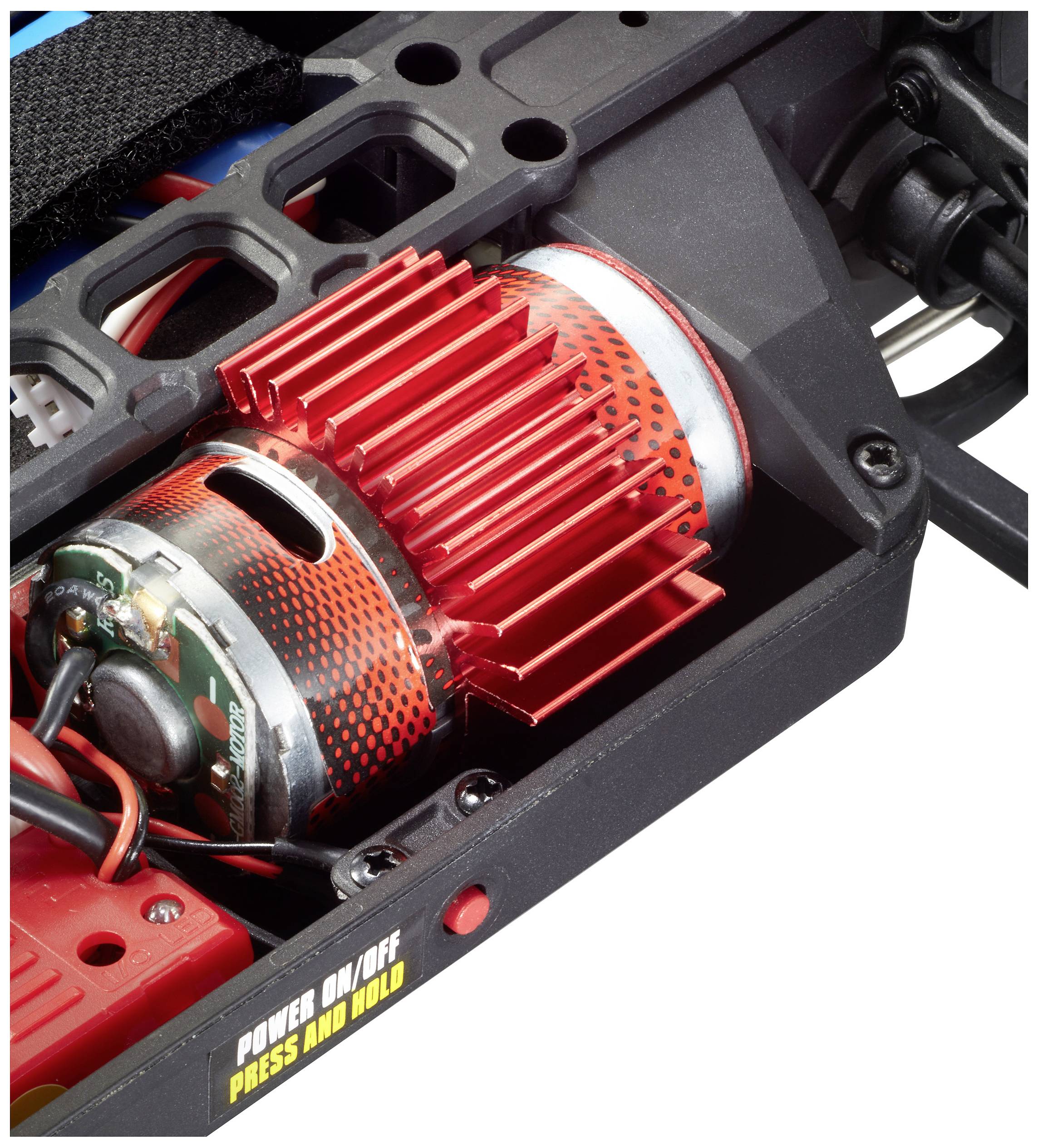 Nahaufnahme eines roten Elektromotors mit Kühlrippen in einem technischen Gerät. Ein gelber Schalter mit 'POWER ON/OFF PRESS AND HOLD'.