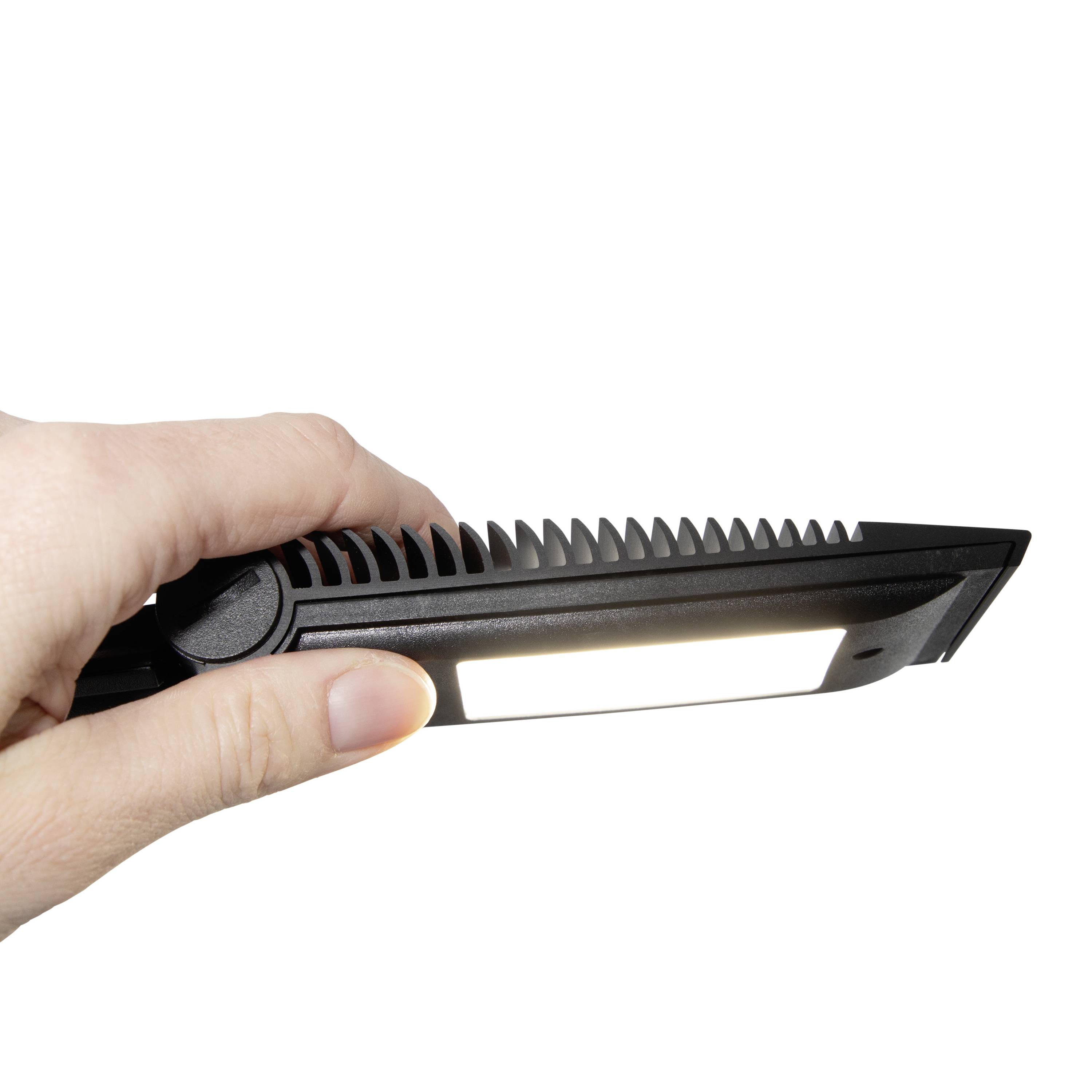 Eine Hand hält ein flaches, rechteckiges Lichtgerät mit gerippten Seiten, das hell leuchtet, vor weißem Hintergrund.