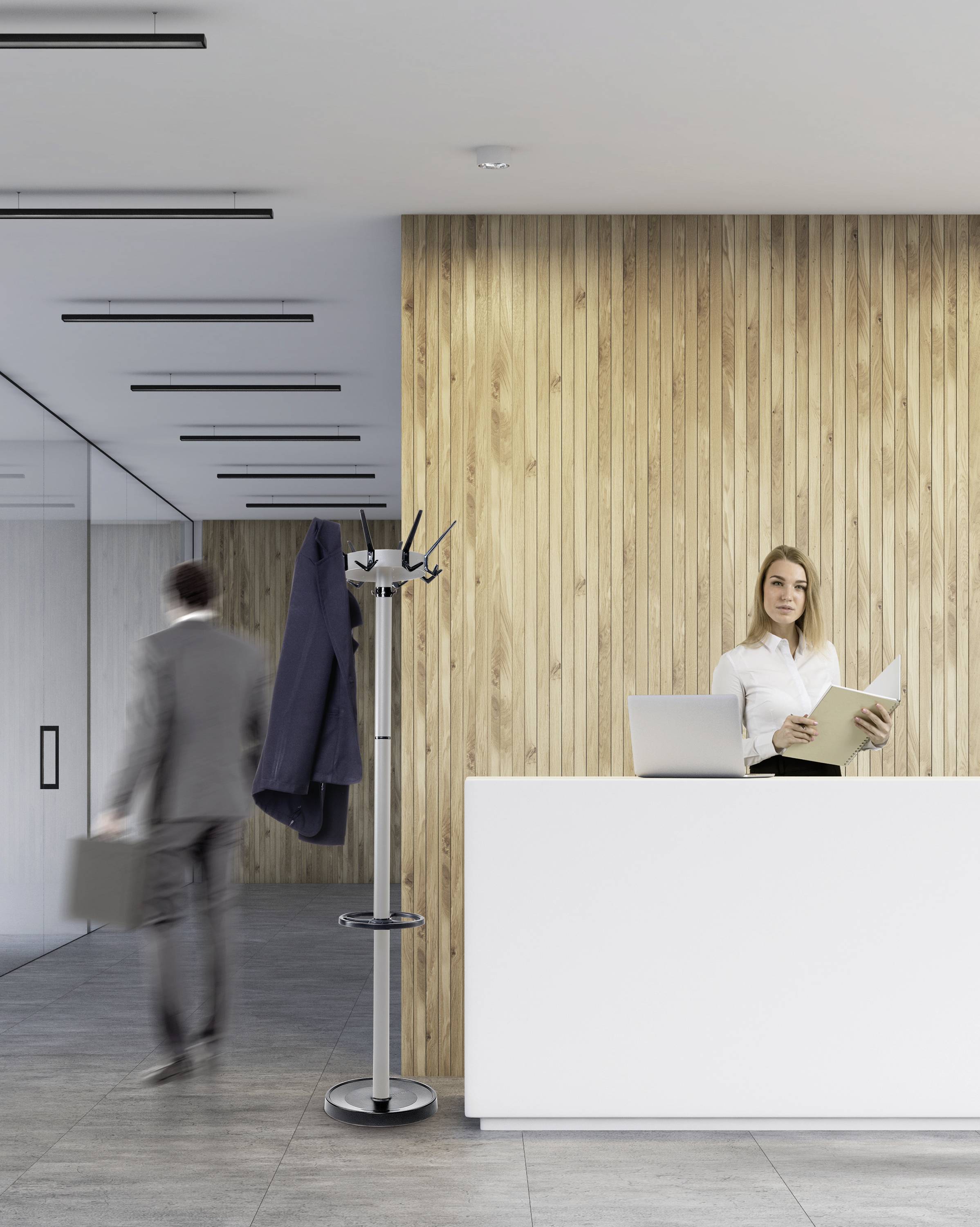 Eine Frau steht hinter einem Empfangstresen in einem modernen Büro. Ein Mann in einem Anzug geht vorbei. Holzwand im Hintergrund.